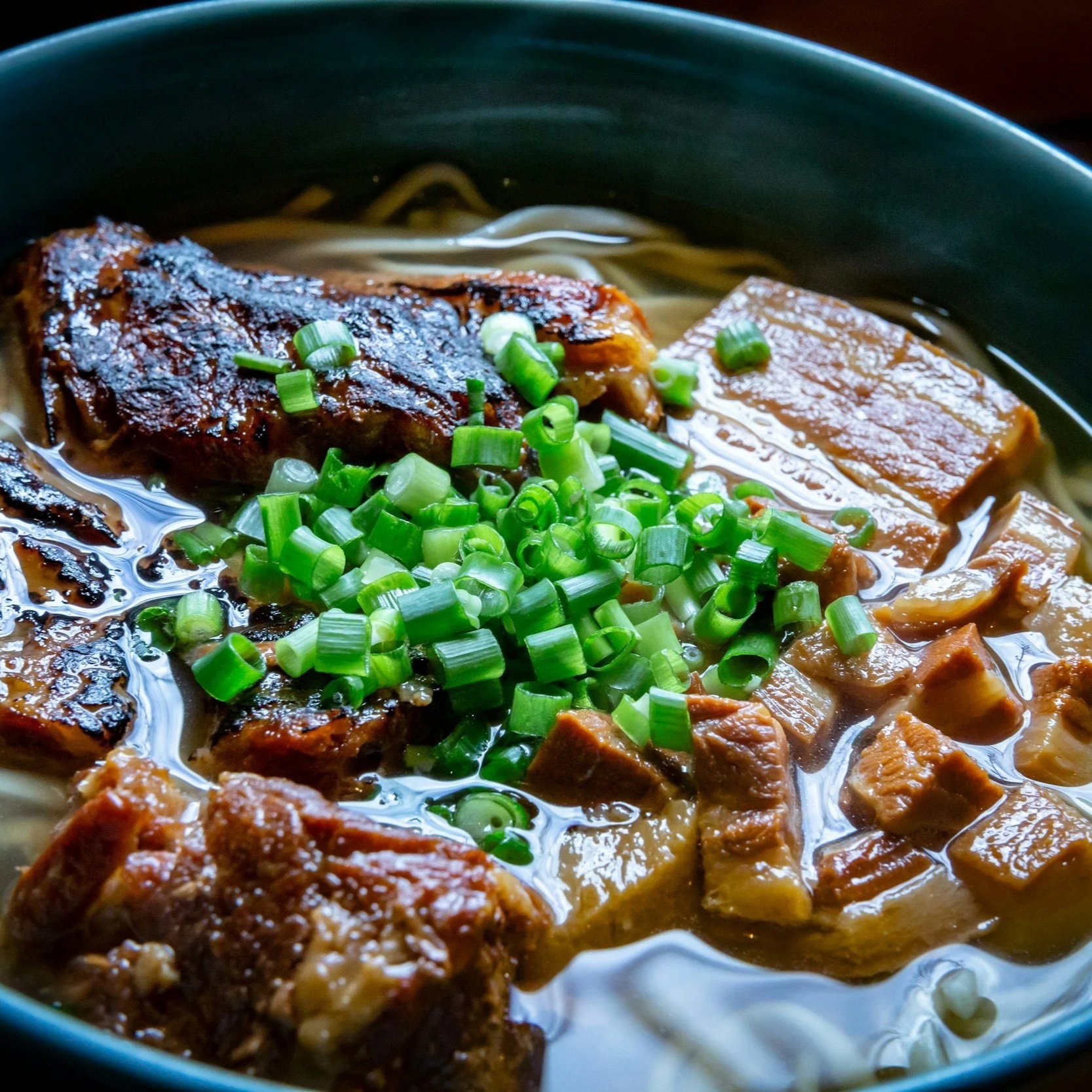 A steaming bowl of Okinawa soba, a beloved island comfort food made with thick wheat noodles, savory broth, and slow-braised pork