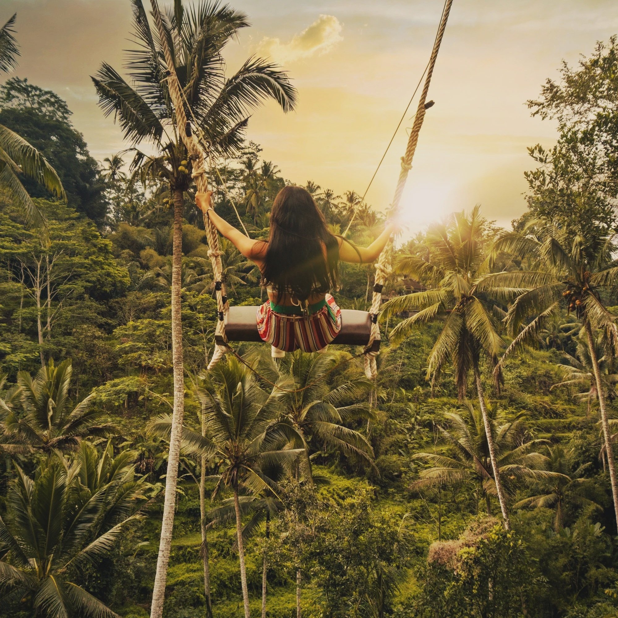 Person on a Bali jungle swing overlooking lush green forest
