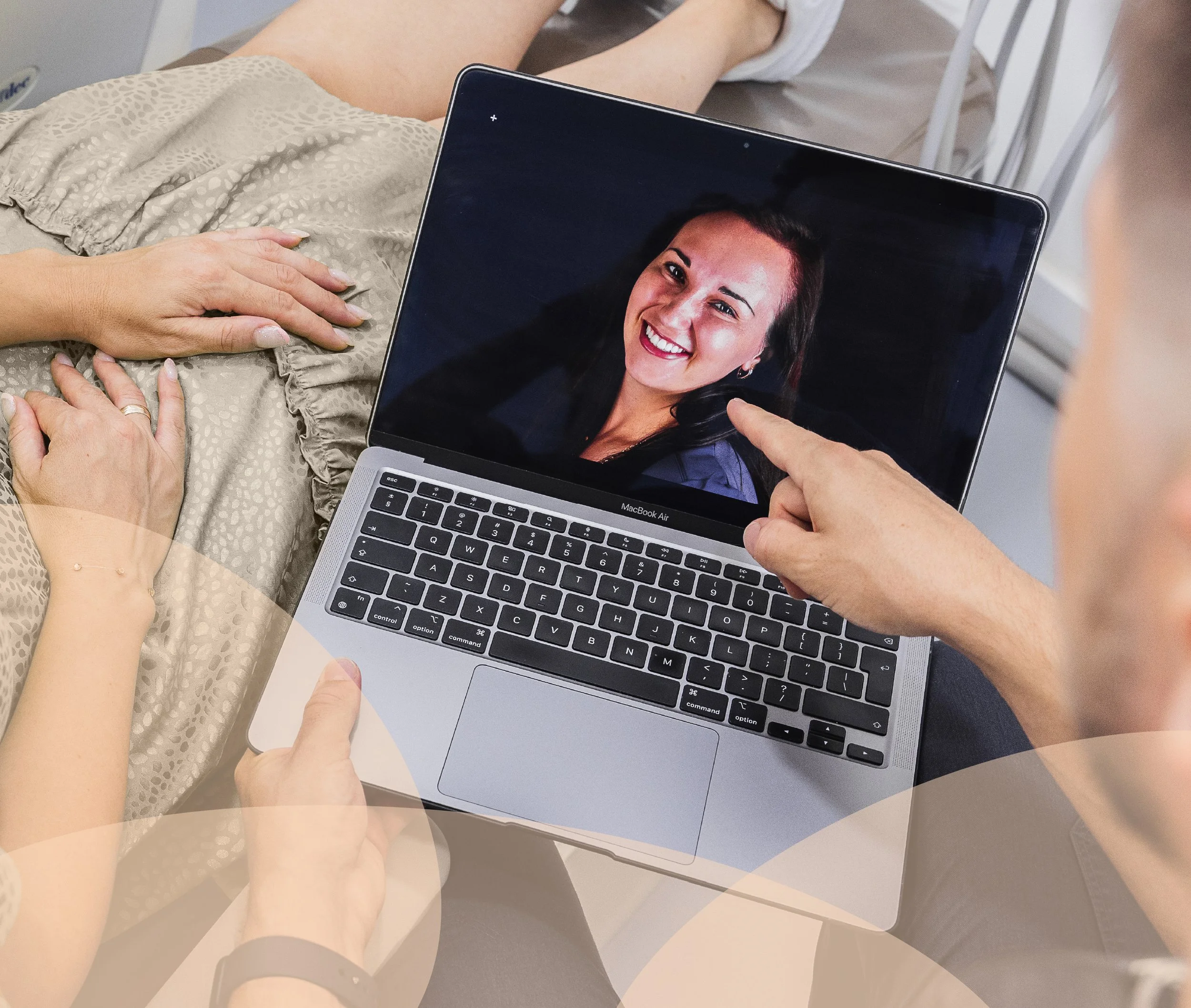 Person pointing at a smiling woman's photo on a laptop screen, with two other people sitting nearby.