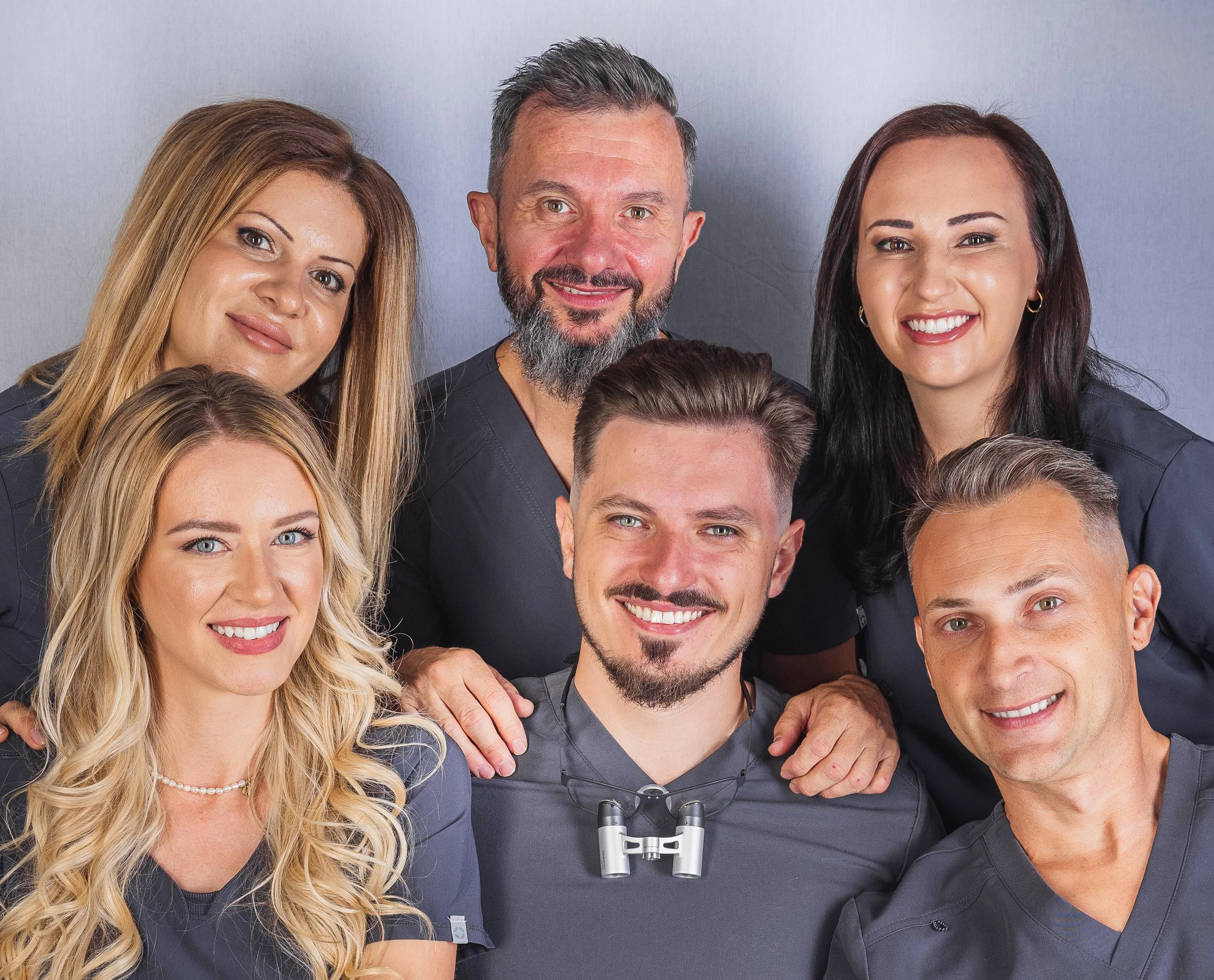 Team MIRORA - healthcare professionals smiling together in medical scrubs against a light gray background.