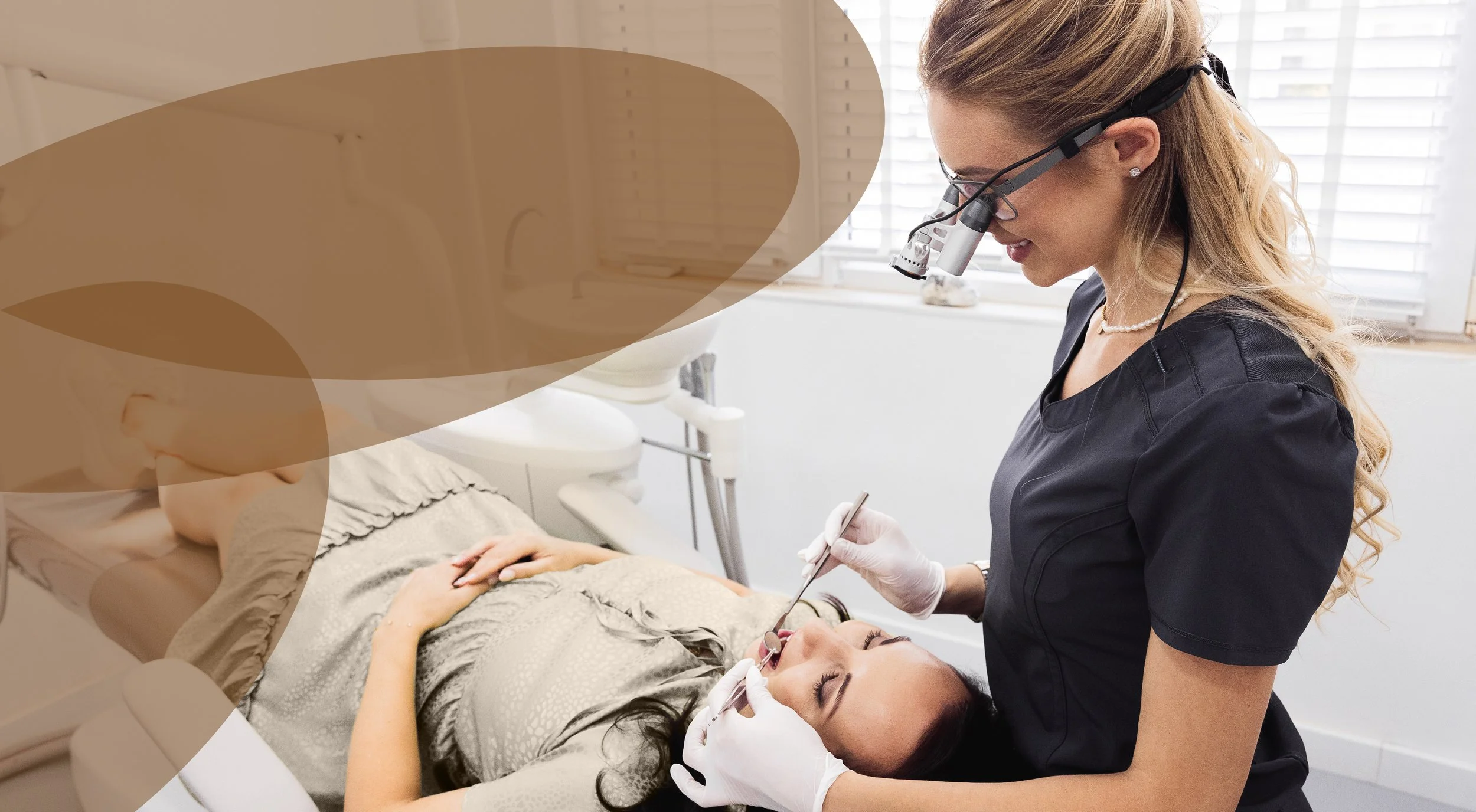 A female dentist wearing magnifying glasses examines a patient's mouth using dental tools in a dental clinic.