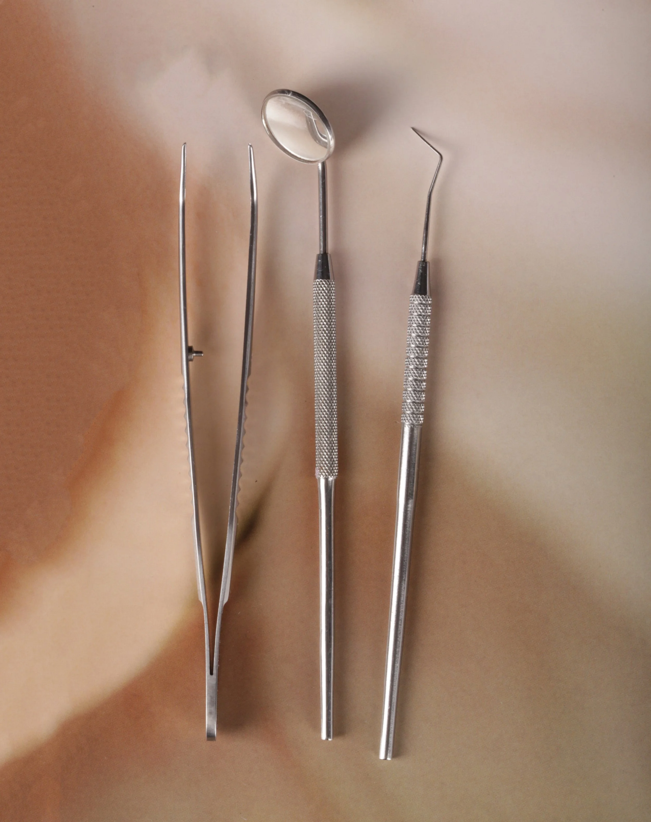 Dental tools including a mirror, two probes, and two picks laid out on a dental examination surface.