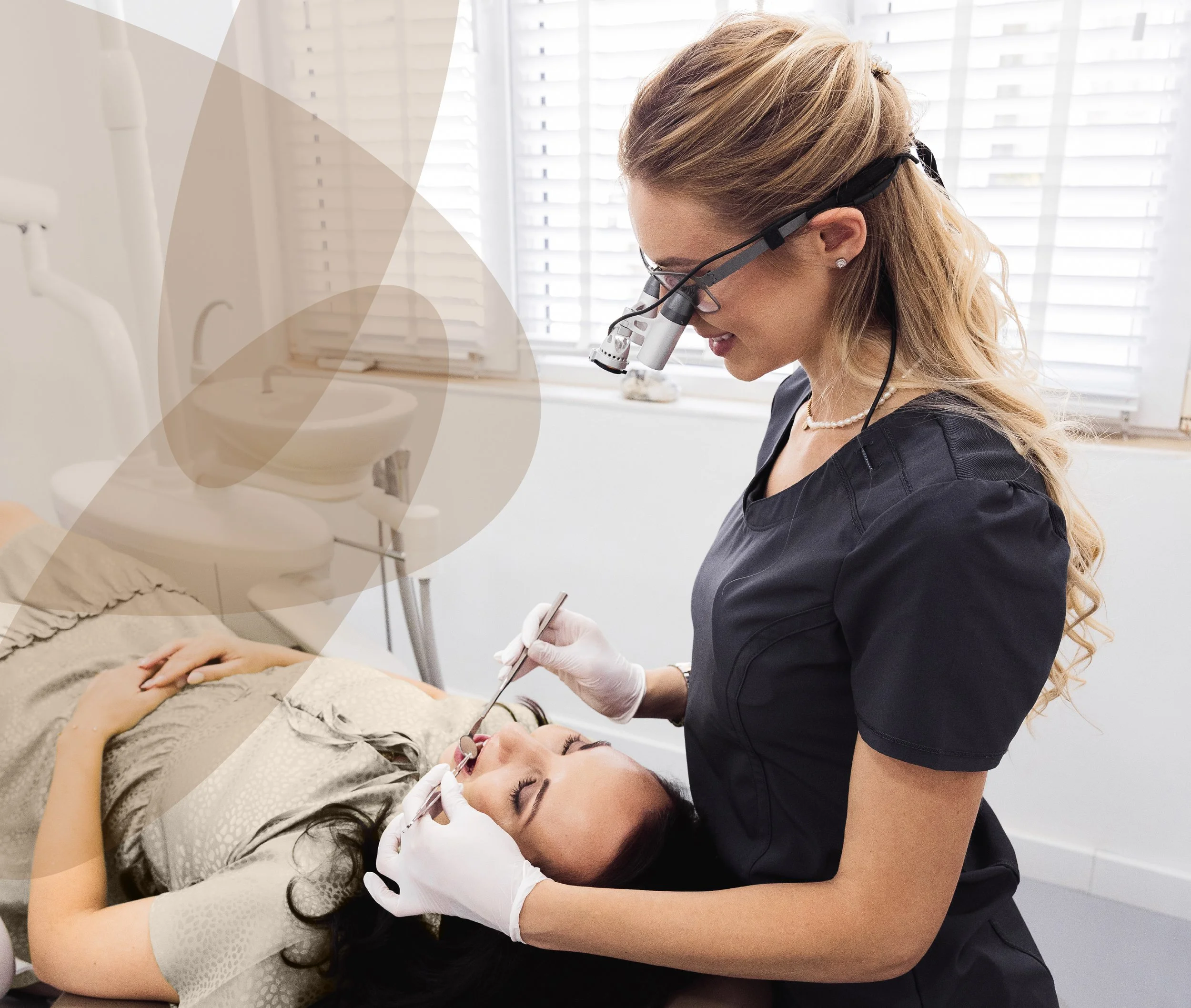 Dental hygienist performing a dental procedure on a woman lying in the dental chair, with dental tools, gloves, and glasses.