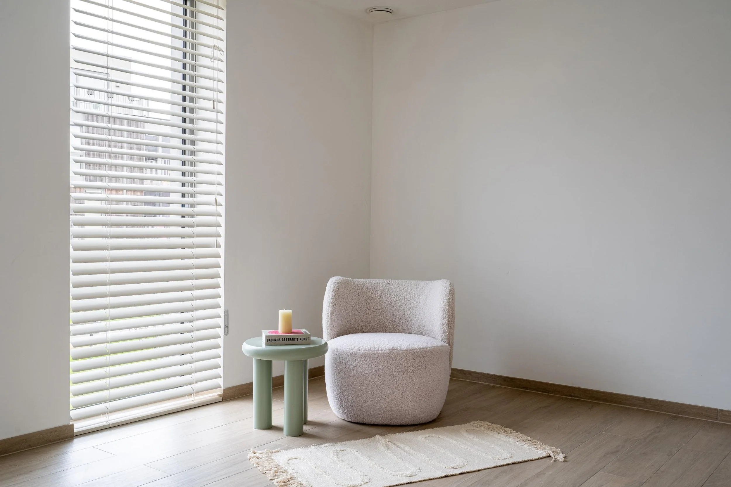 Een sober modern salon met eenzit en leestafel te Gent