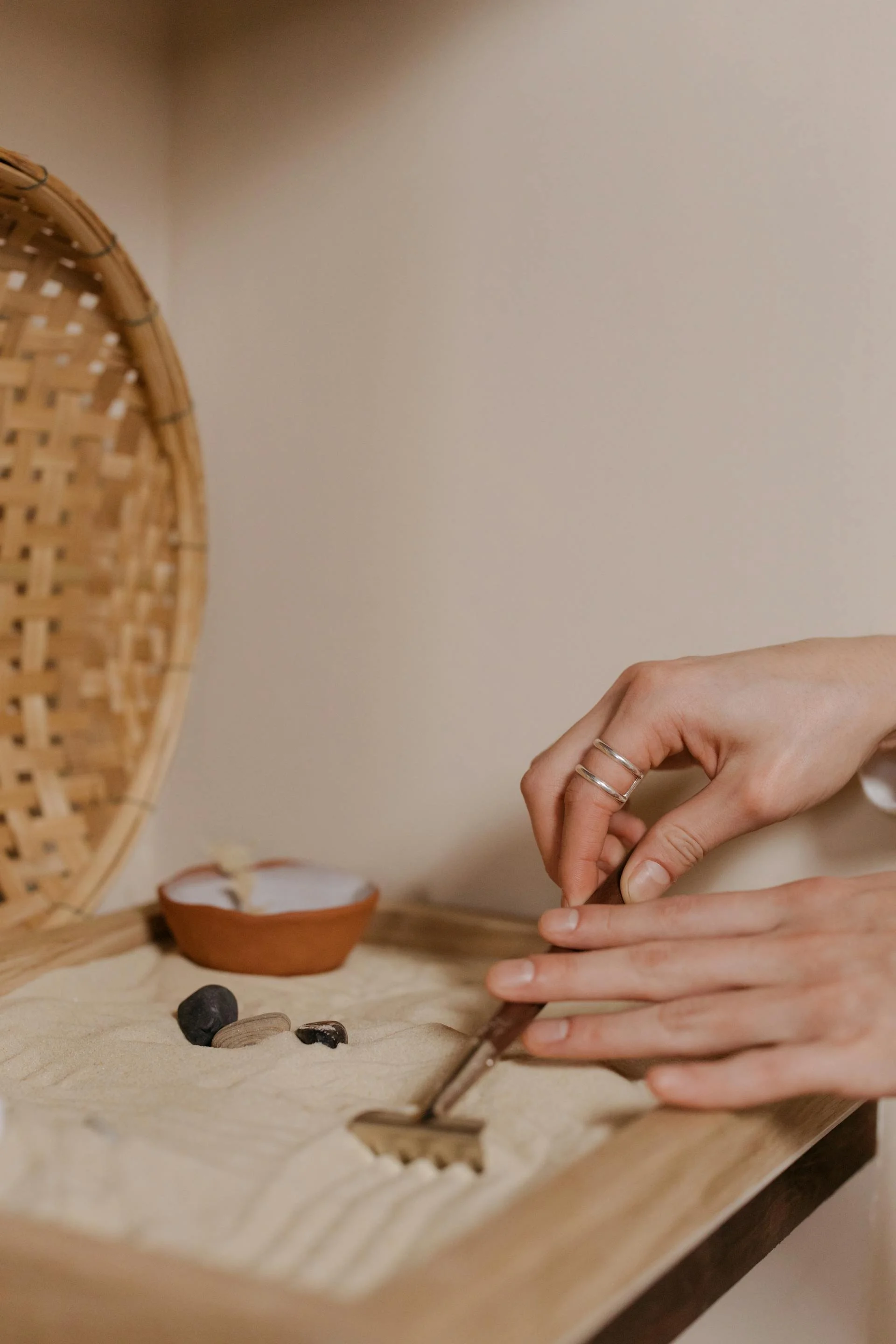 Custom Squarespace Template, Portfolio Squarespace Template, Avelã Creative. Hands arranging a miniature zen garden with sand and small stones, using a tiny rake, next to a small clay bowl.
