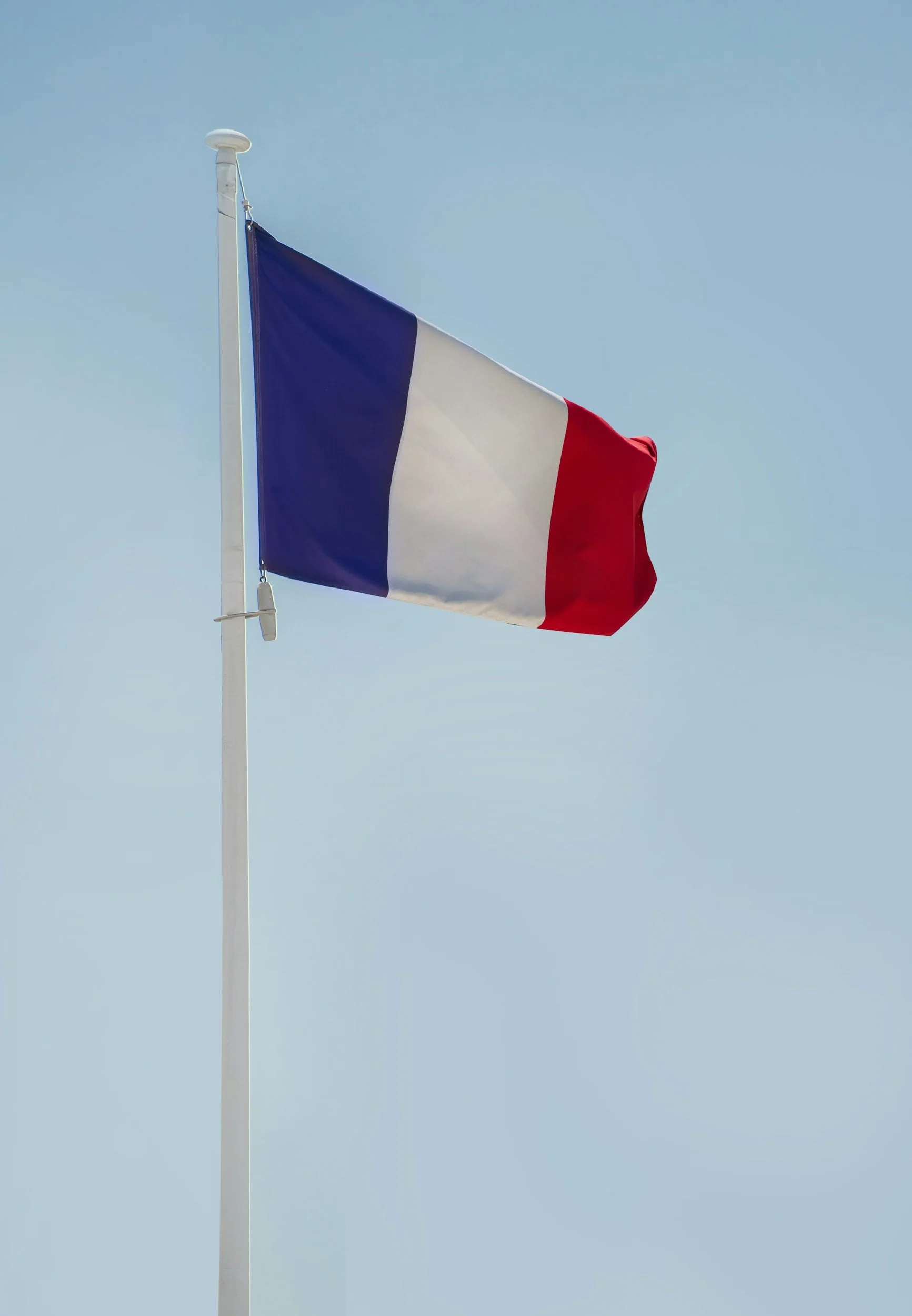 Mountain range with snow-capped peaks, green rolling hills with a modern building in the foreground, cloudy sky.
