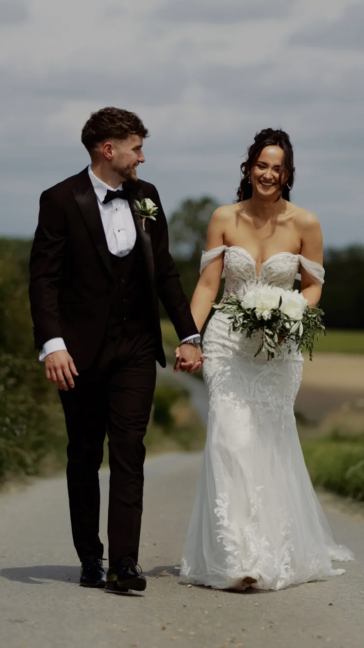 Bride and groom walking hand in hand along a path
