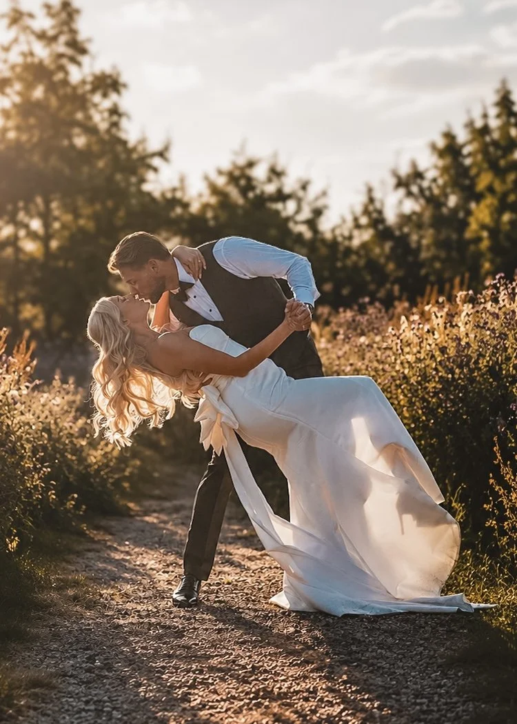 Groom dipping bride on a sunlit country path