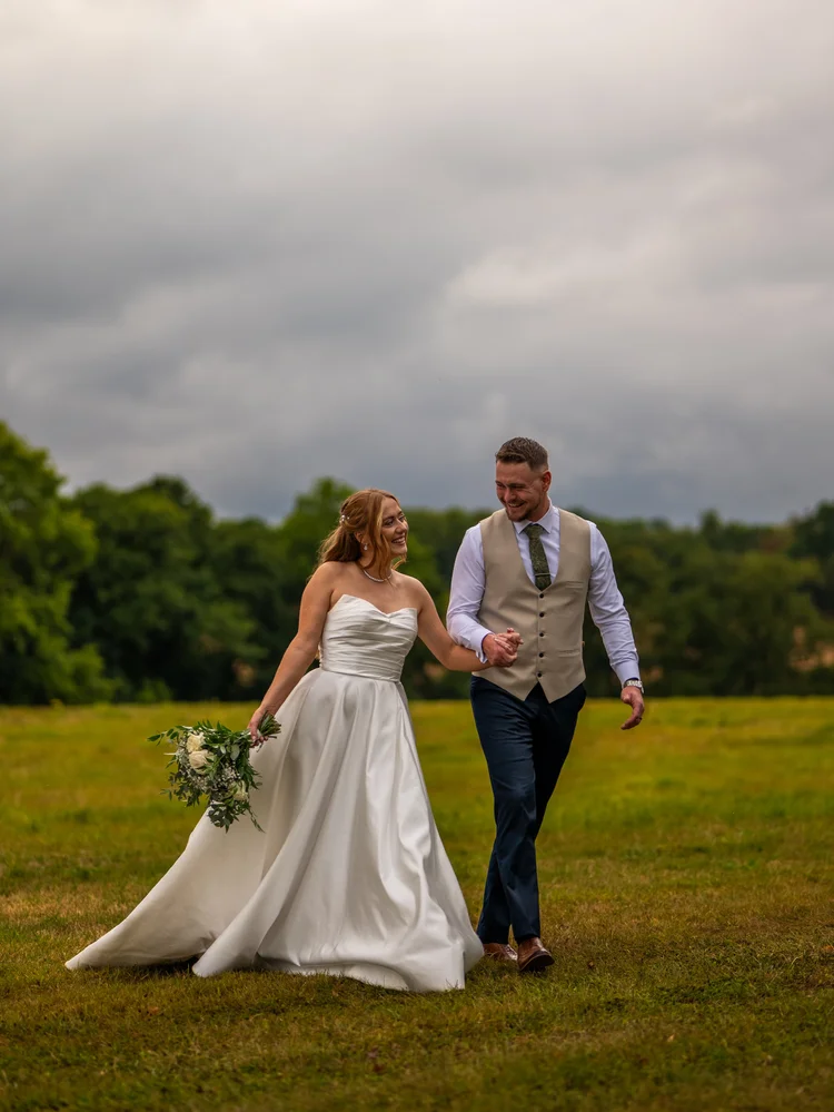 Bride and groom strolling across a grassy field