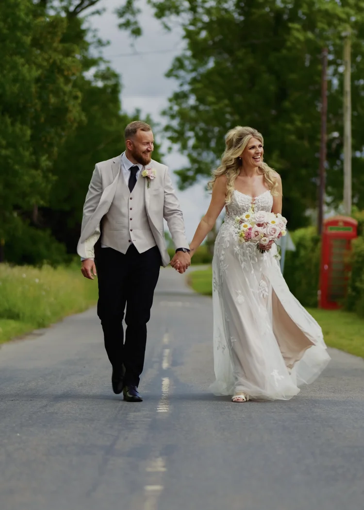 Bride and groom walking hand in hand down a country lane