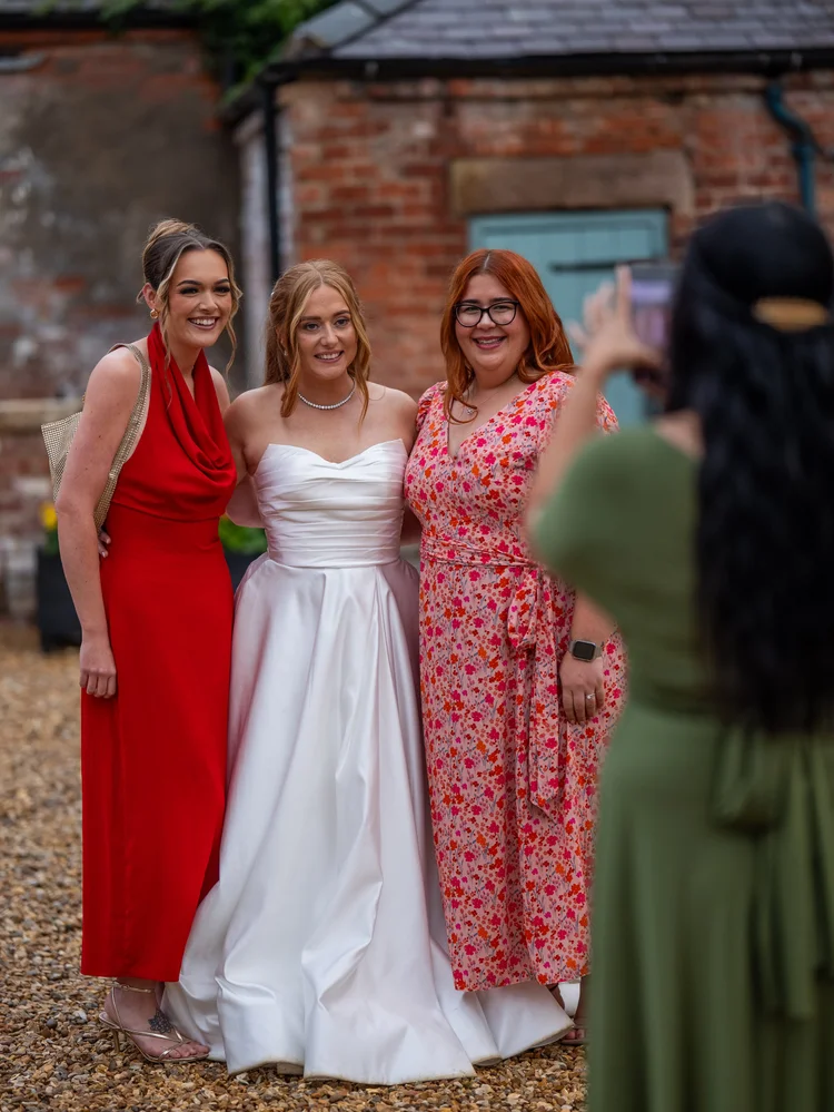 Bride posing with guests outside a brick building