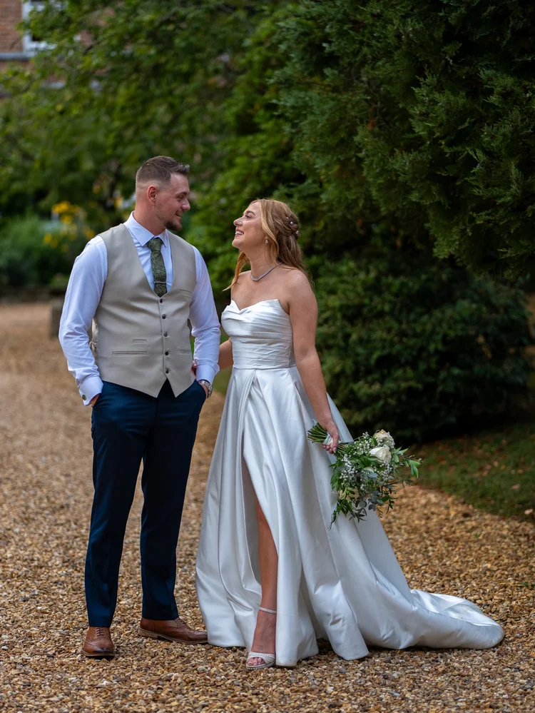 Bride laughing as groom looks on, holding her bouquet