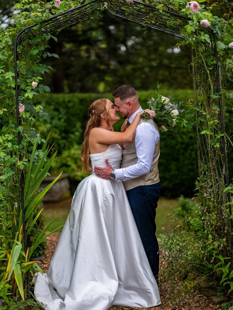 Bride and groom embracing under a rose arch