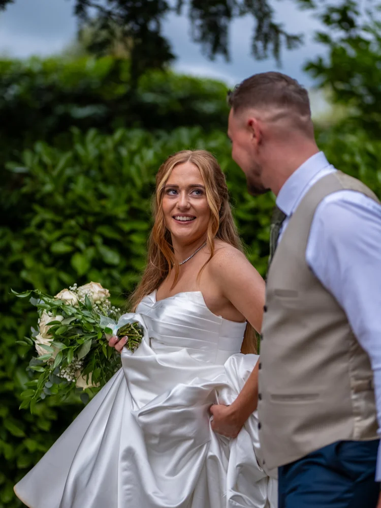 Bride smiling at the camera as groom looks at her