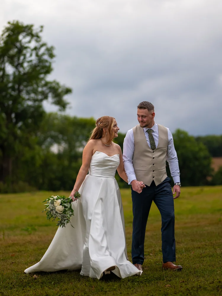 Bride and groom walking together across a field