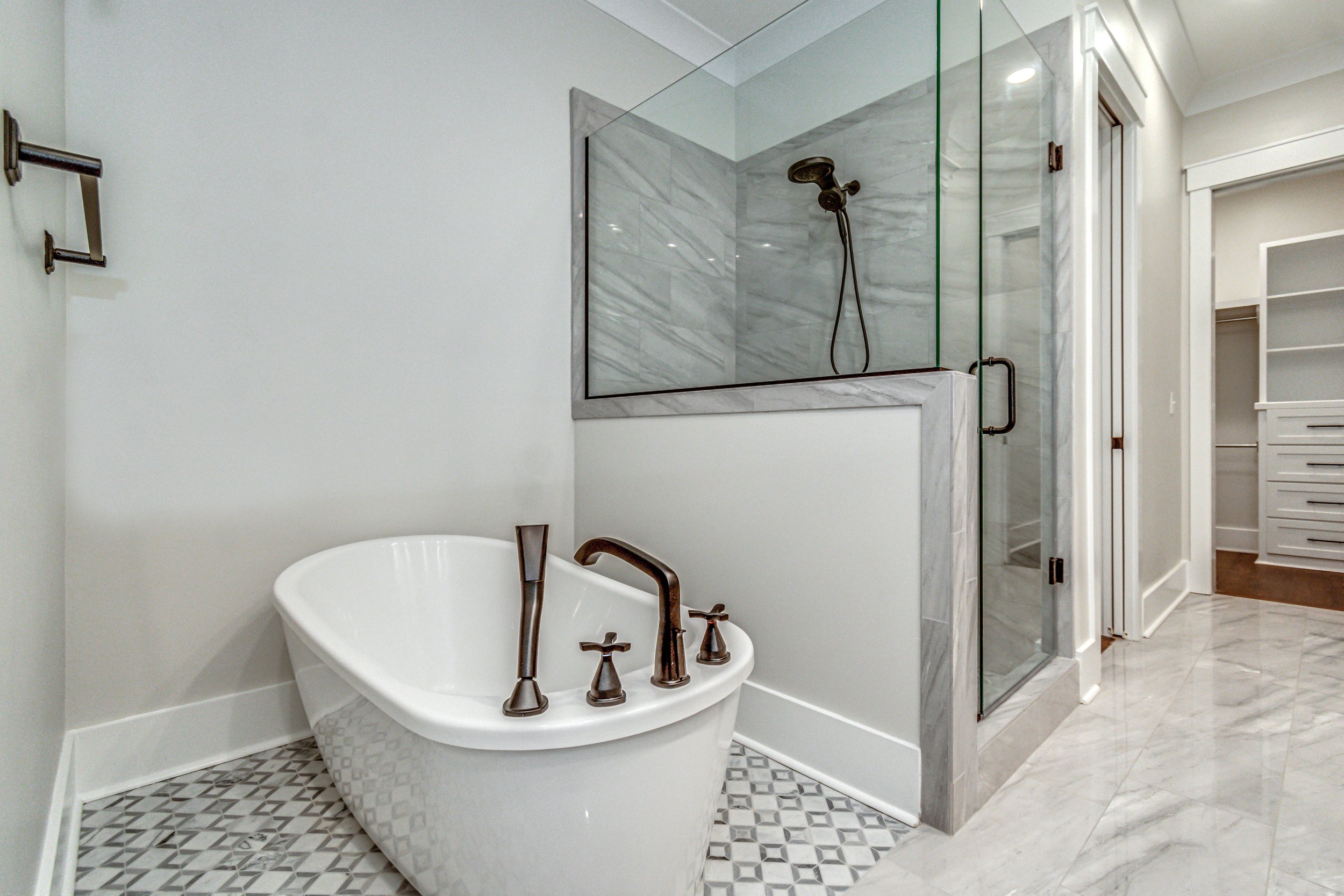 Modern bathroom with a white freestanding bathtub, and a glass-enclosed shower with gray marble tiles.