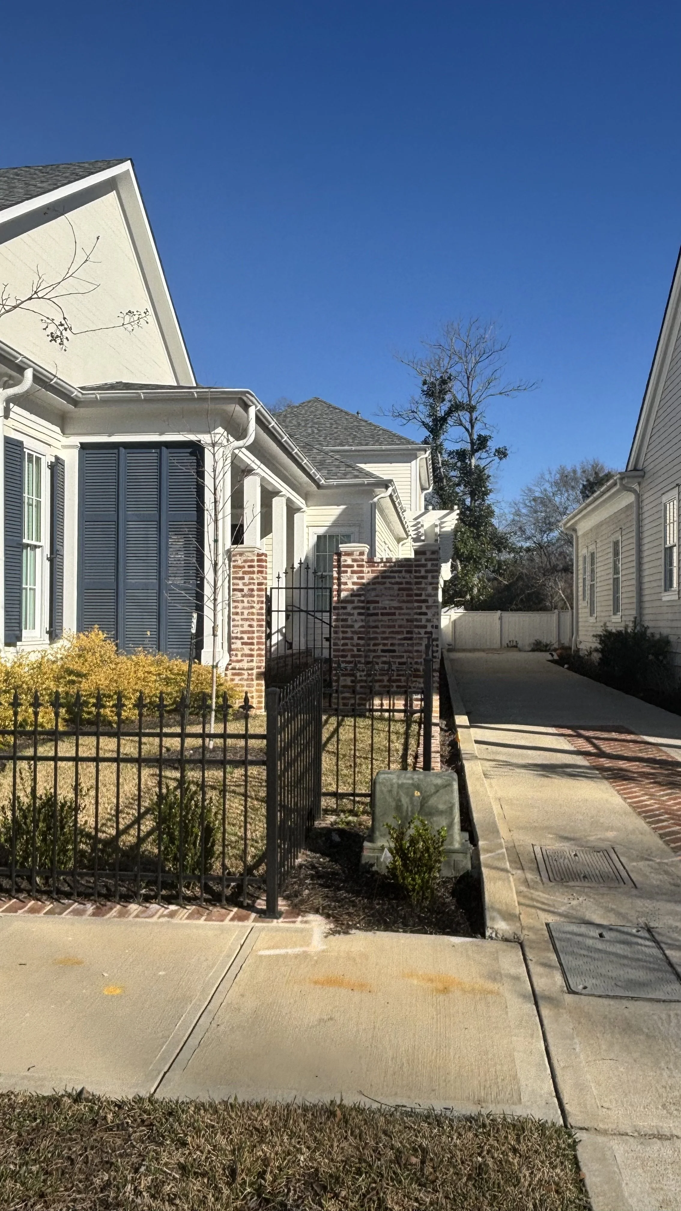 Residential neighborhood with houses, sidewalk, fence, and clear blue sky.