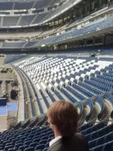 Empty stadium seats with a person in the foreground watching.