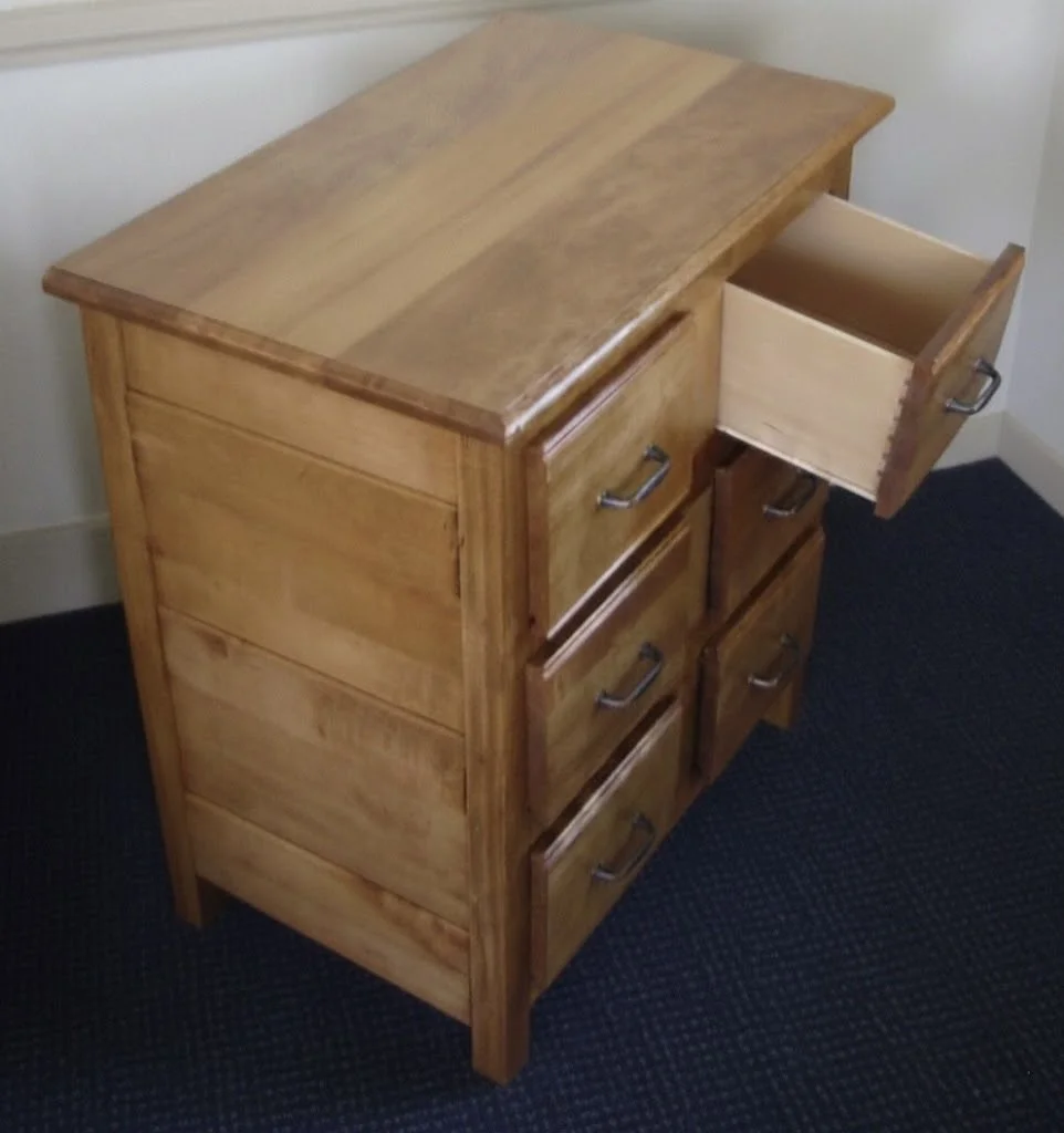 A wooden desk with multiple drawers, one of which is open, revealing an empty interior.