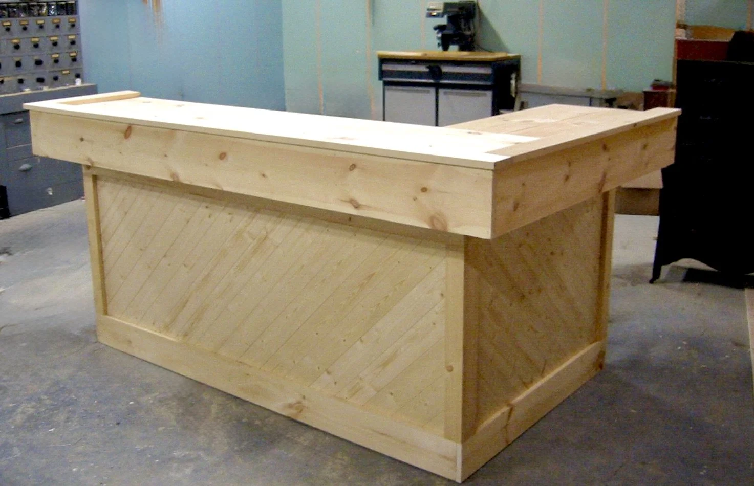 unfinished wooden bar counter with diagonal wood paneling in a workshop.