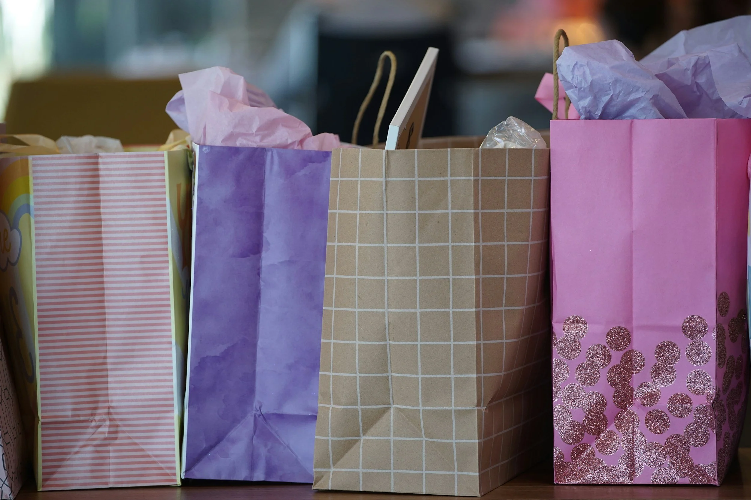 Colorful paper gift bags with tissue paper inside, arranged on a table.