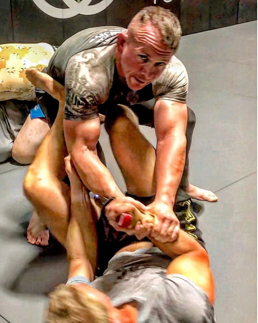 Two men fighting on the ground, one gripping the other’s face, in a confrontational physical altercation.