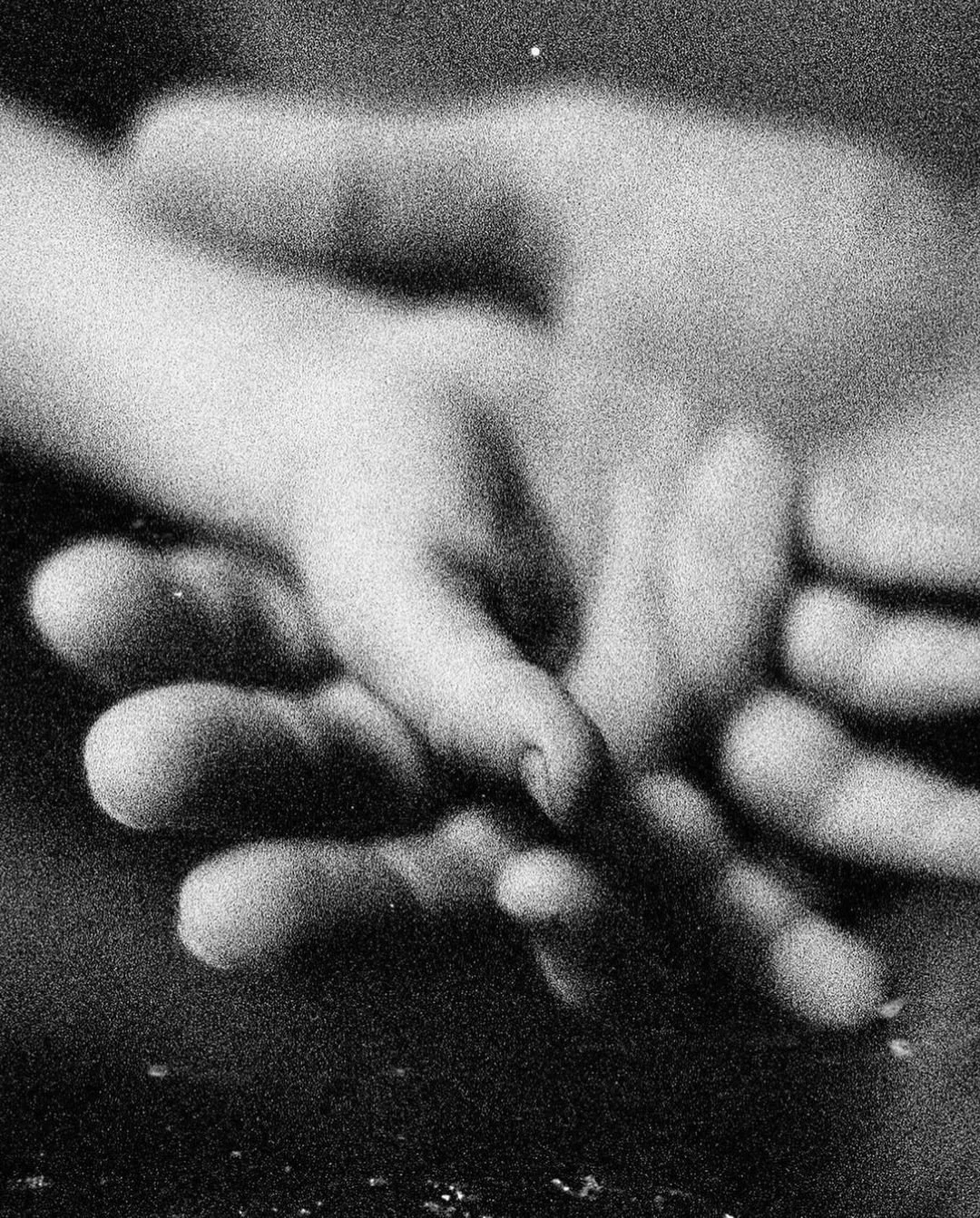 Two people holding hands in black and white, representing connection and support