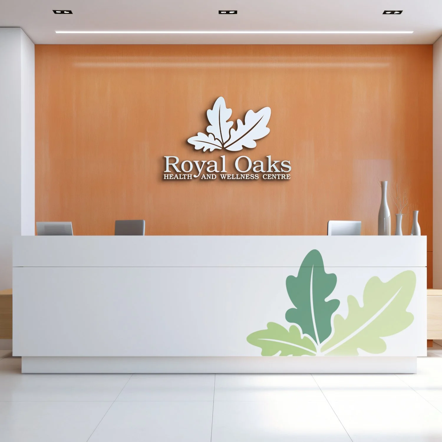 Reception desk at Royal Oaks Health and Wellness Centre with a white counter decorated with a green leaf design, a wood-paneled wall behind with a large white leaf logo and the name 'Royal Oaks'