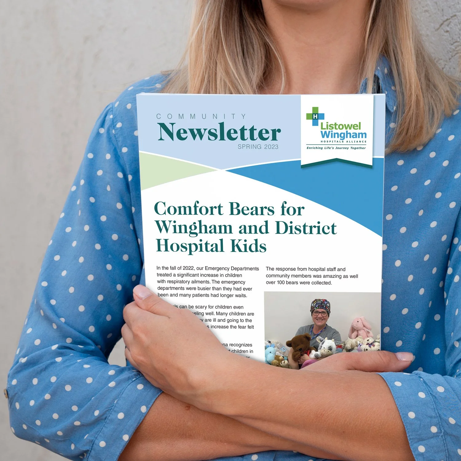 A person dressed in a blue polka dot shirt is holding a newsletter titled 'Community Newsletter Spring 2023' with the headline 'Comfort Bears for Wingham and District Hospital Kids'.