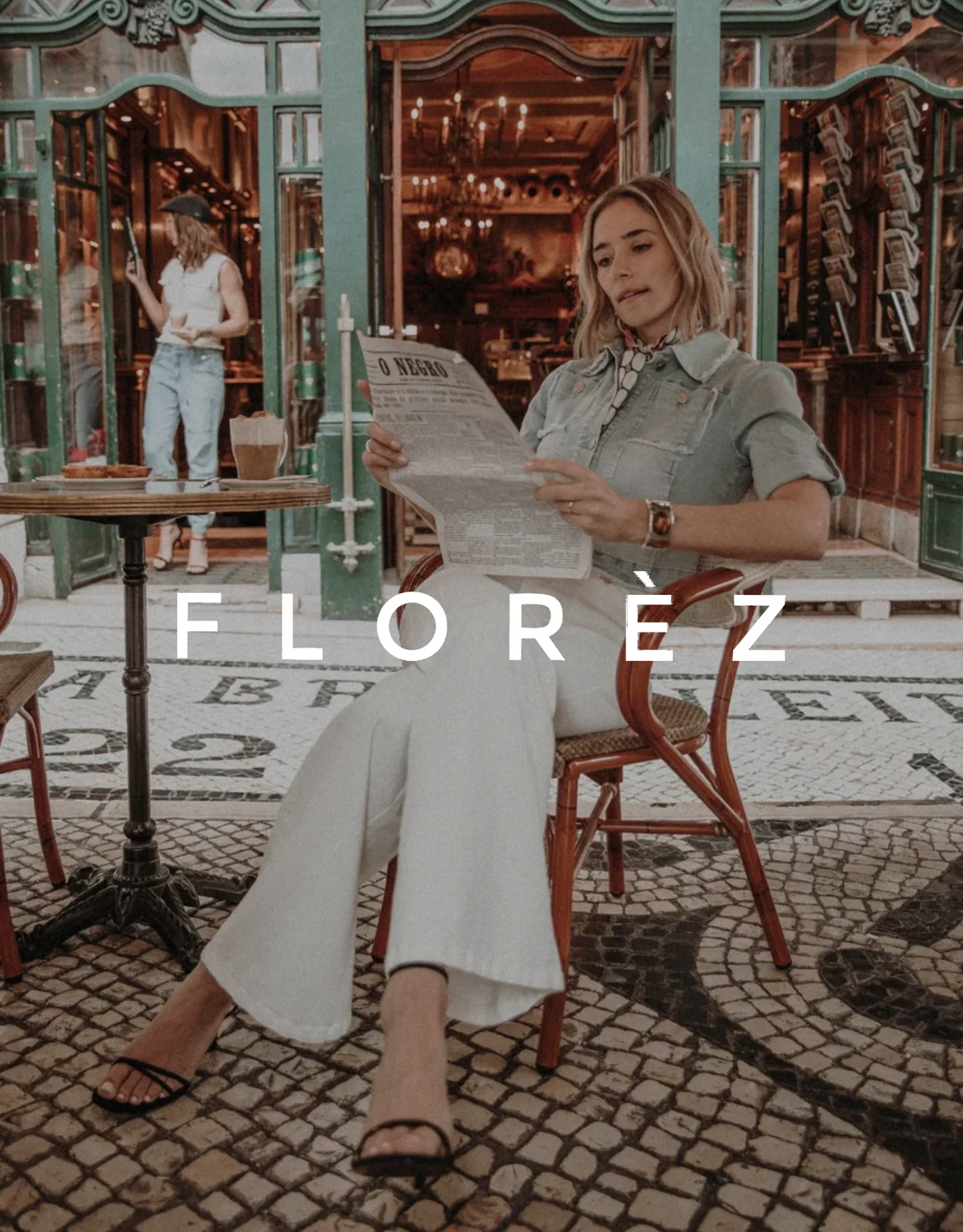 A woman sitting at a table reading a newspaper in a vintage-style cafe, with another woman in a white outfit in the background. The scene is warm and cozy, with decorative flooring and ornate interior details. The word 'Florez' is prominently displayed across the image.