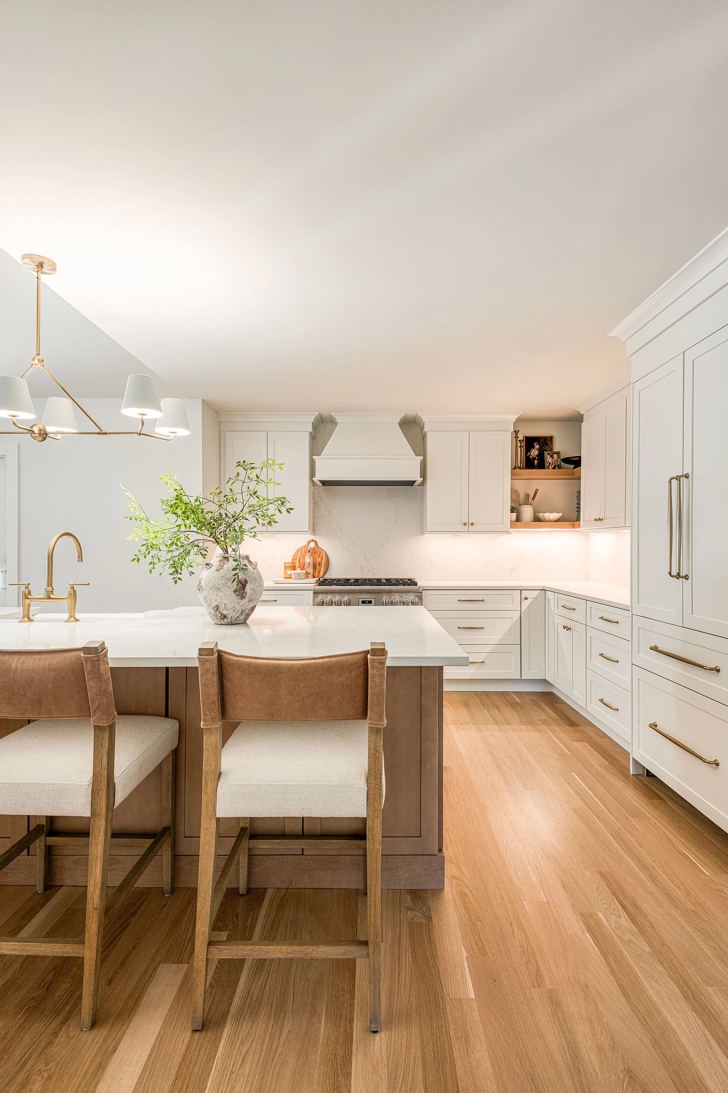 Modern kitchen with a quartz counter and backsplash, upholstered and leather counter stools, modern island lighting, open shelving, white oak floors, Fabuwood cabinets, light and bright kitchen renovation 