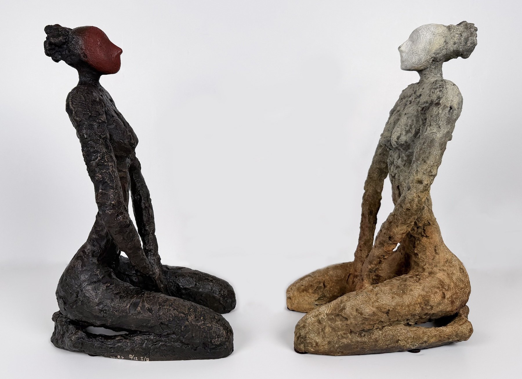 Bronze sculptures of two seated female figures in nude, facing each other