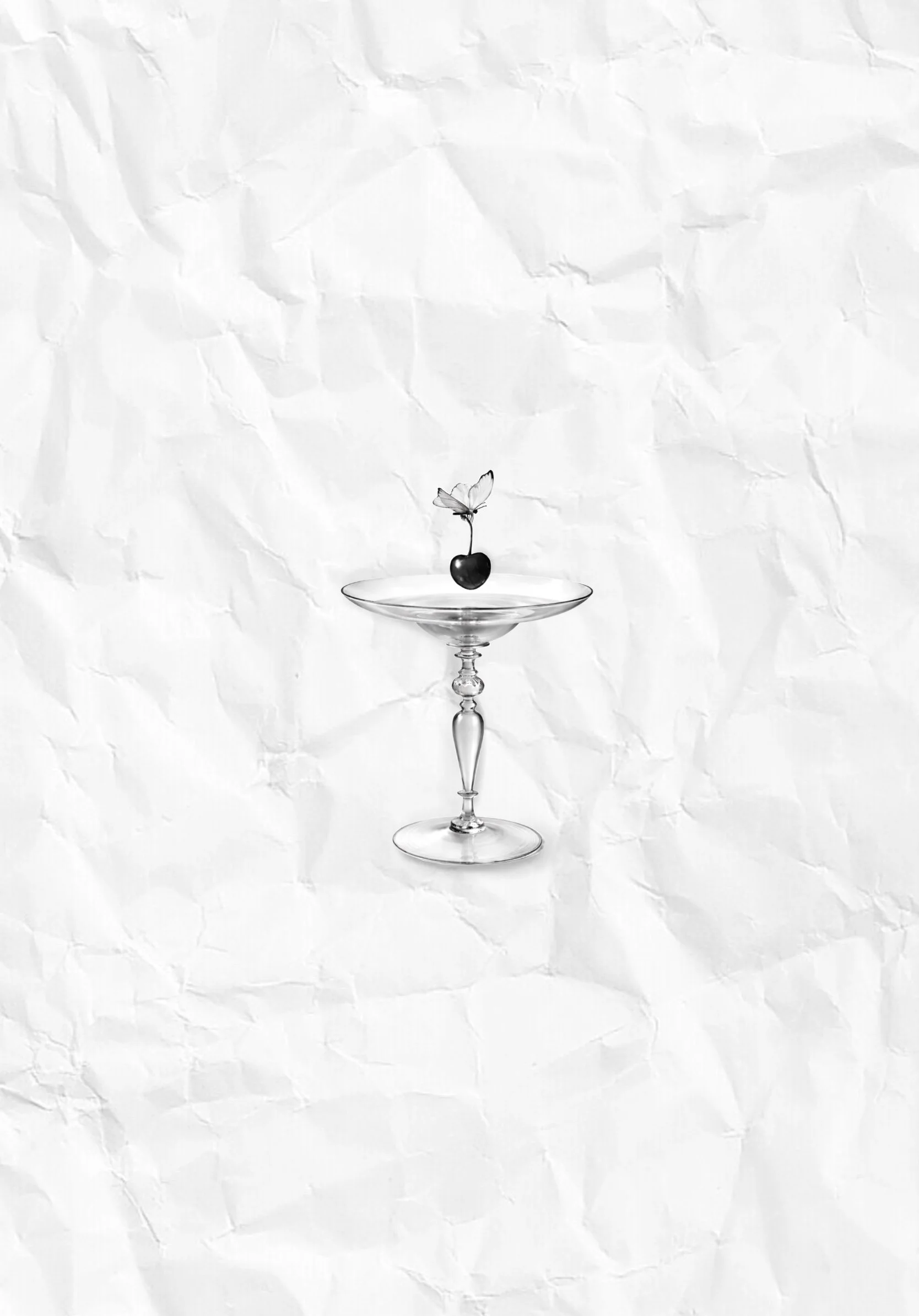 A black cherry with a butterfly perched on its stem, balanced on a clear glass coupe on a white paper background.