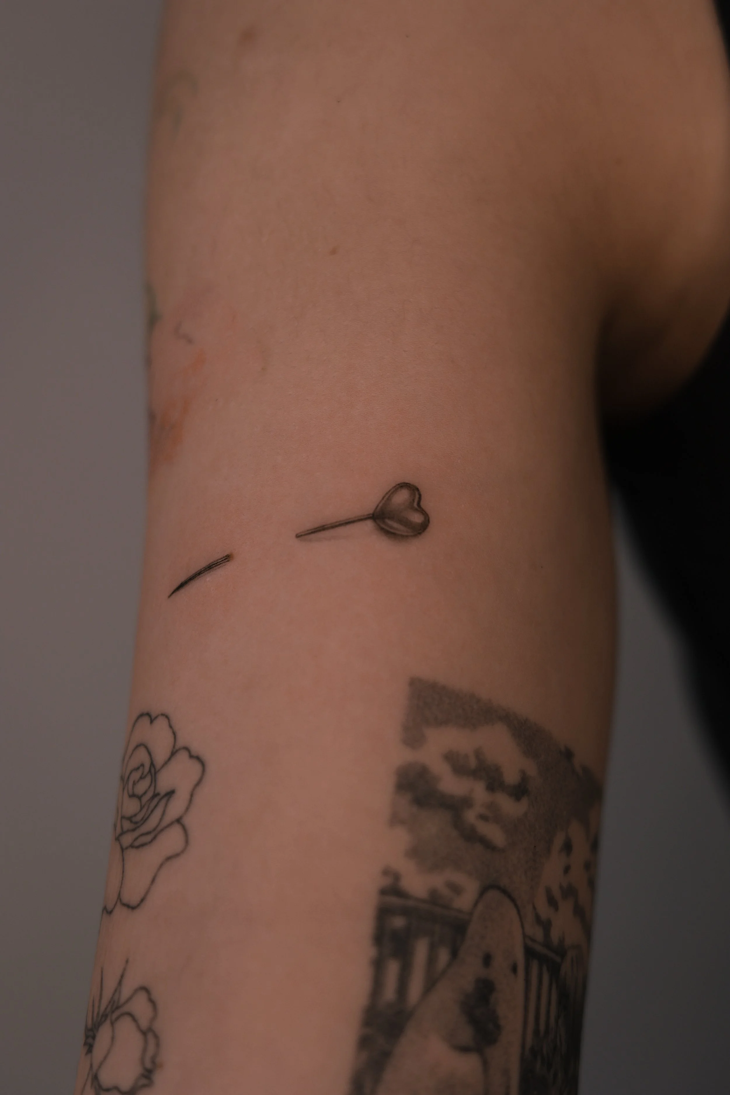 Fine-Line und Micro-Realism Tattoo einer Nadel mit herzförmiger Perle, filigran gestochen