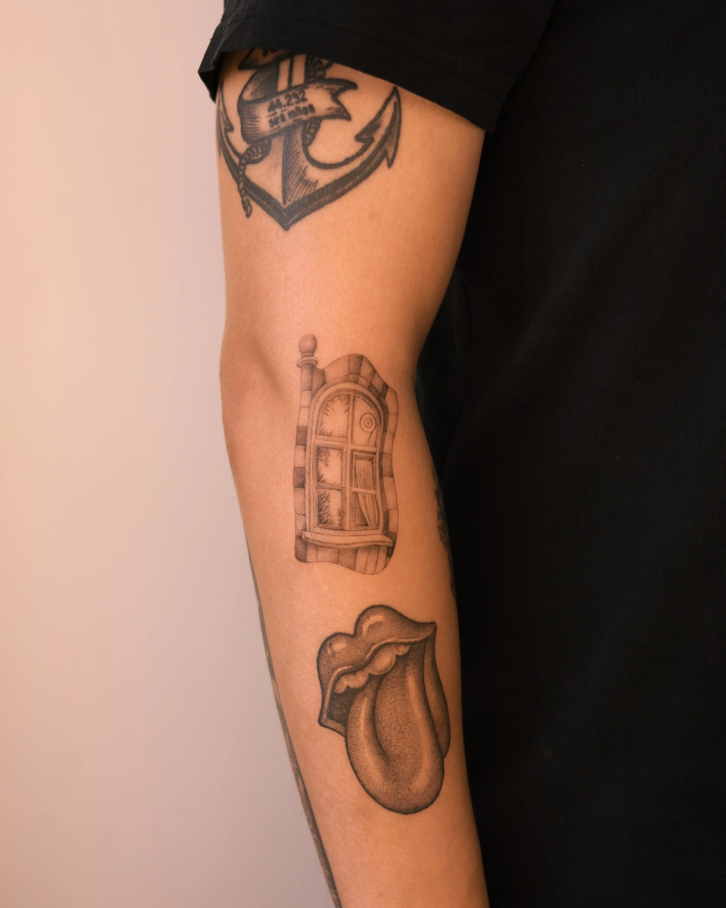 Black and grey micro realism tattoo of an arched window inspired by Hundertwasser’s architecture, on the arm, created by a Vienna tattoo artist as a travel souvenir.