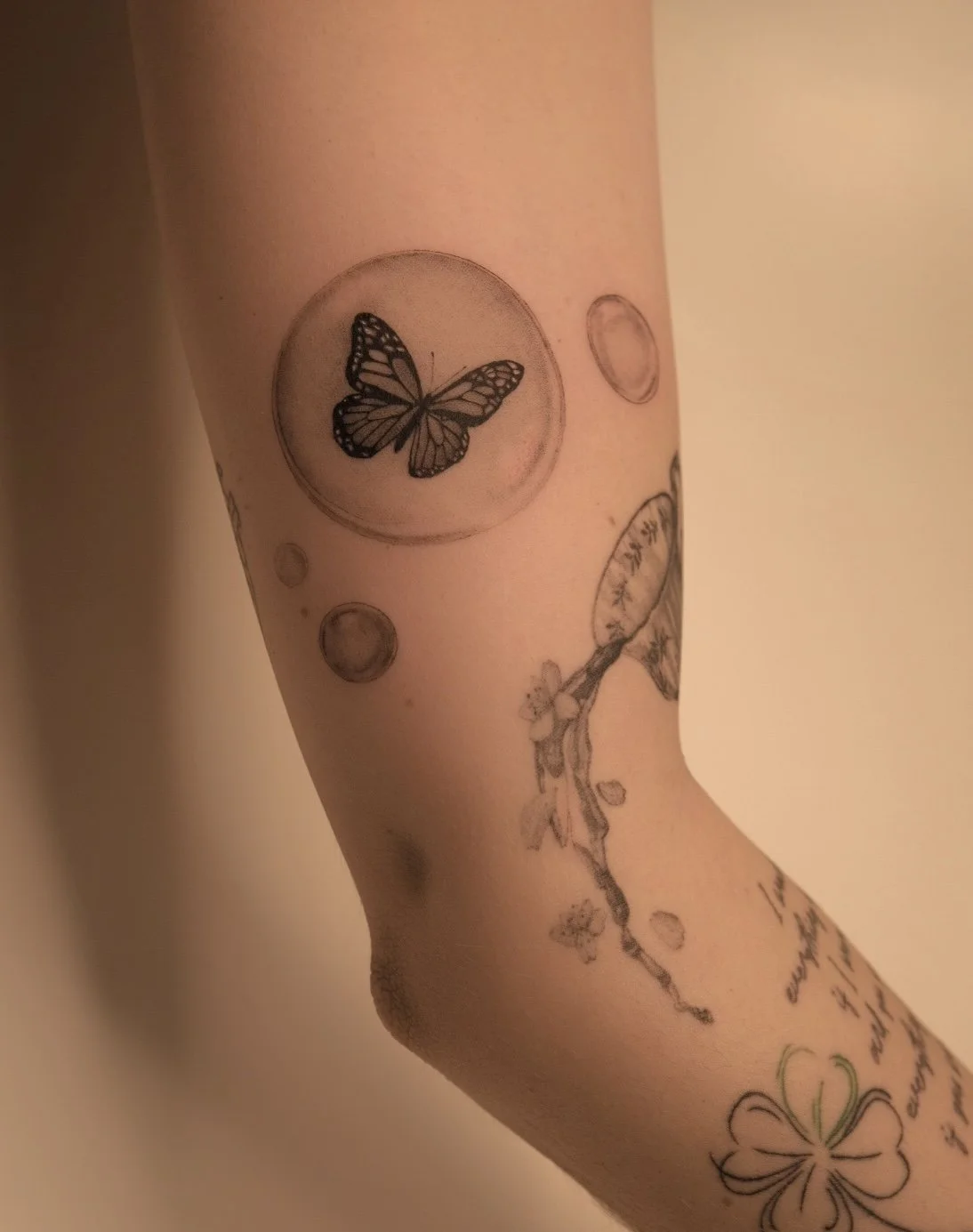 Schmetterling in Seifenblase – Fineline/Mikro-Realismus-Tattoo an der Arminnenseite; sanfte Schattierung, klare Konturen – Wien.