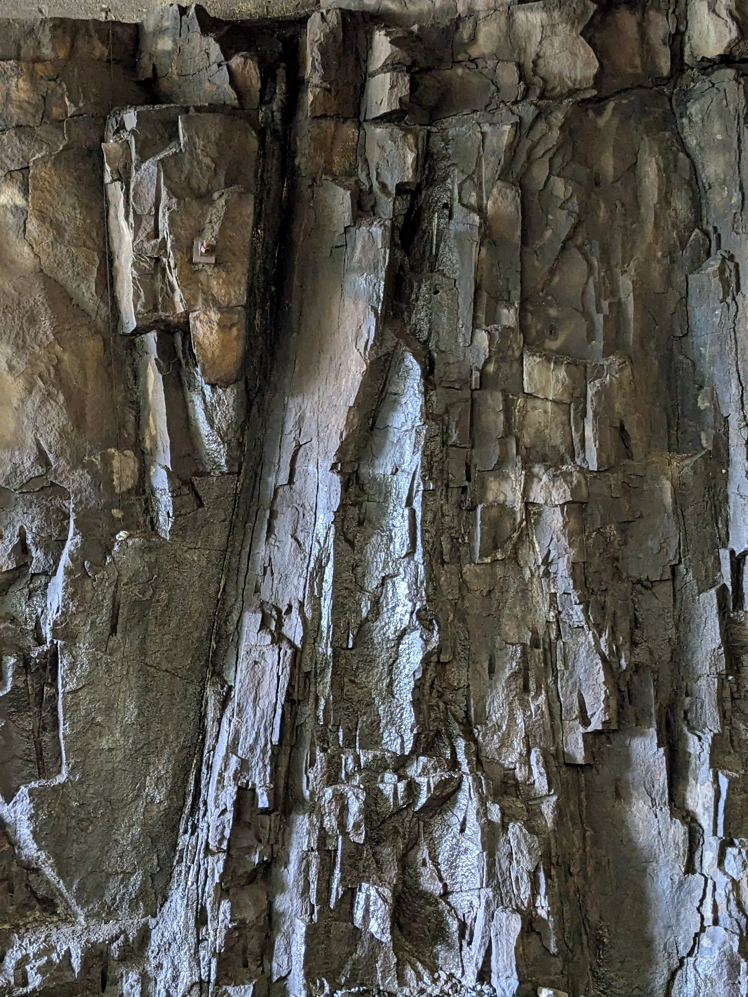 Close-up of a rocky wall with jagged, uneven stone surfaces and cracks.