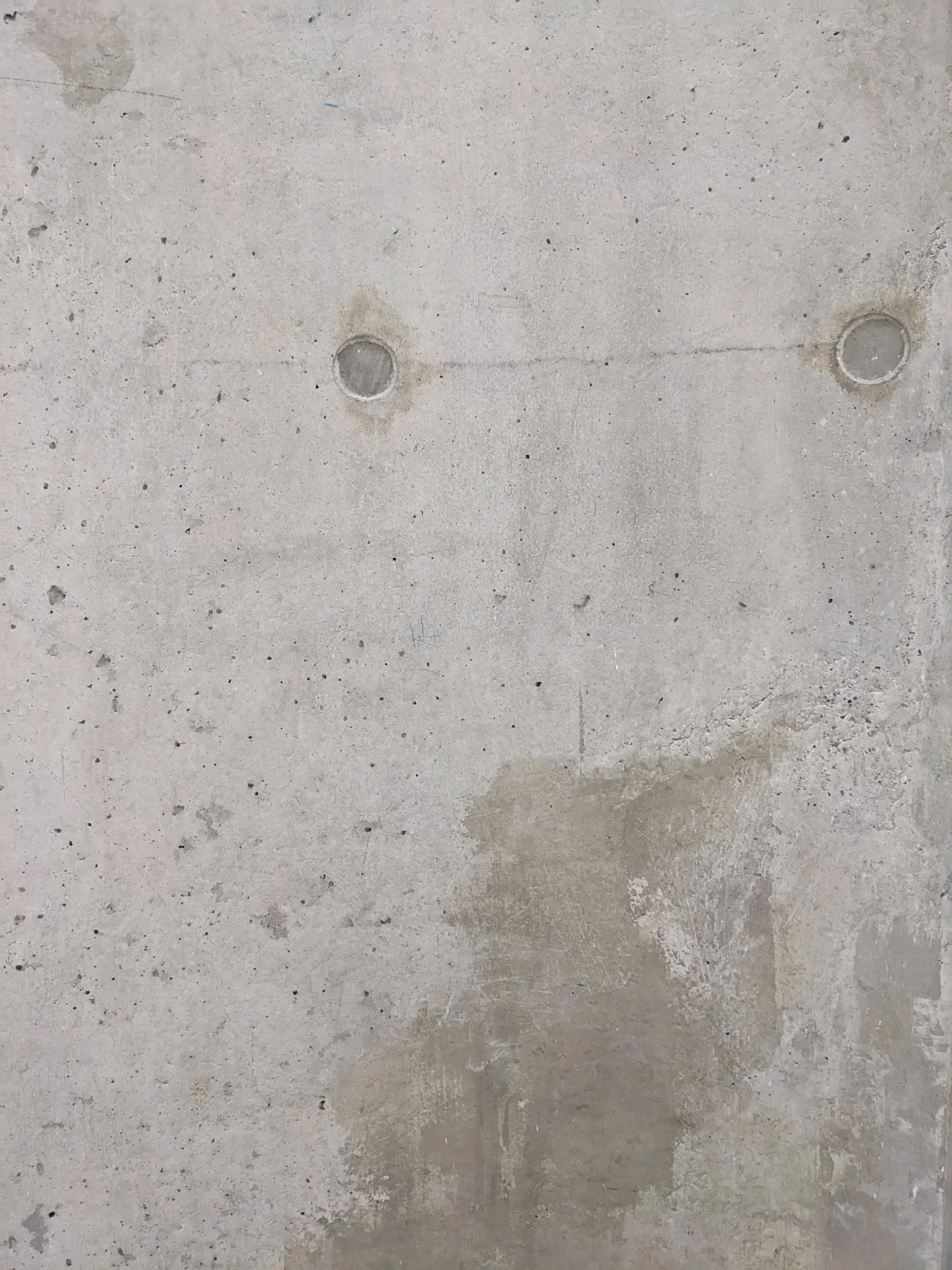 Concrete floor with visible surface cracks, small aggregate particles, and four circular metal access covers.