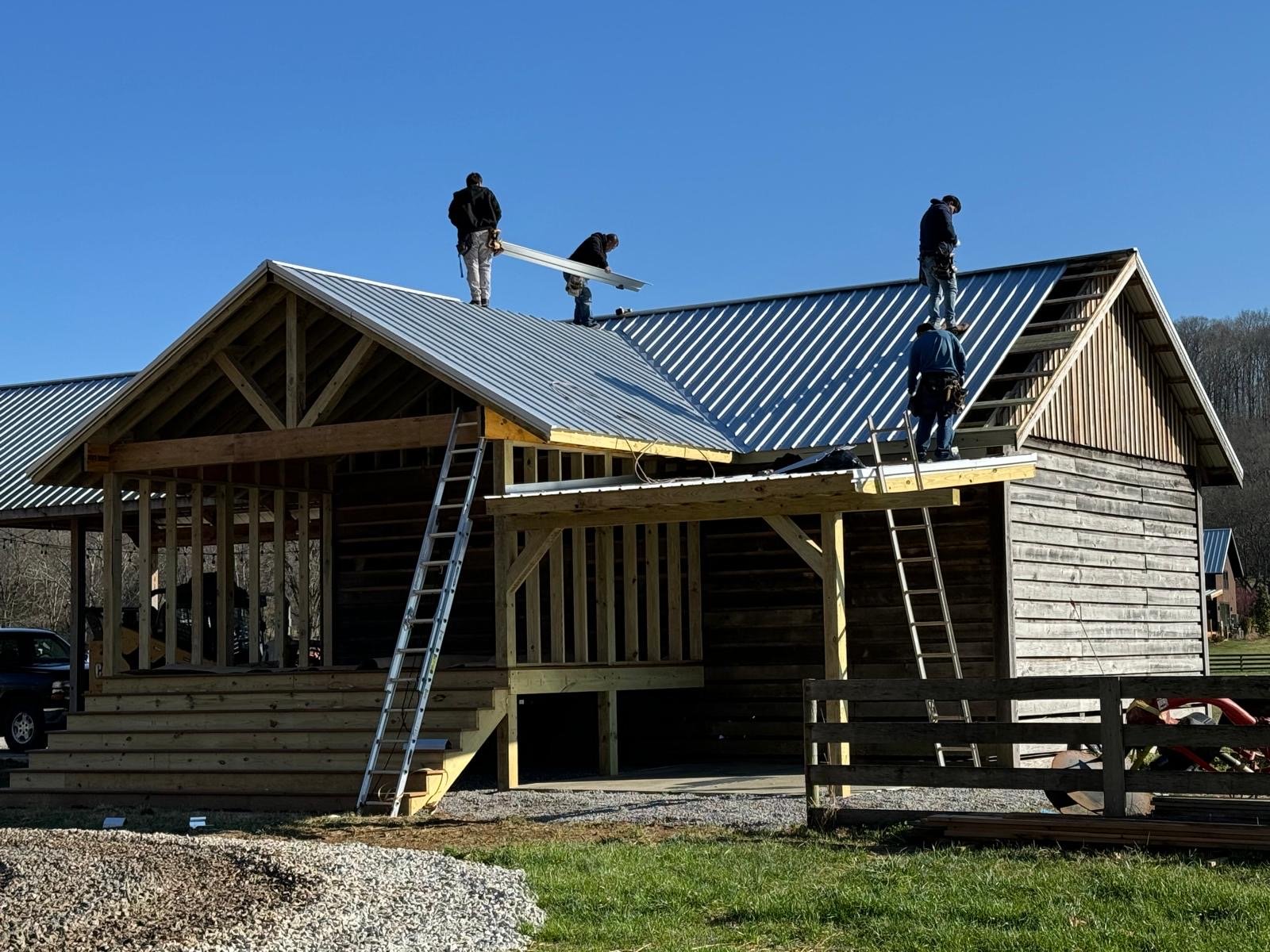 Construction workers installing a metal roof on a wooden house.