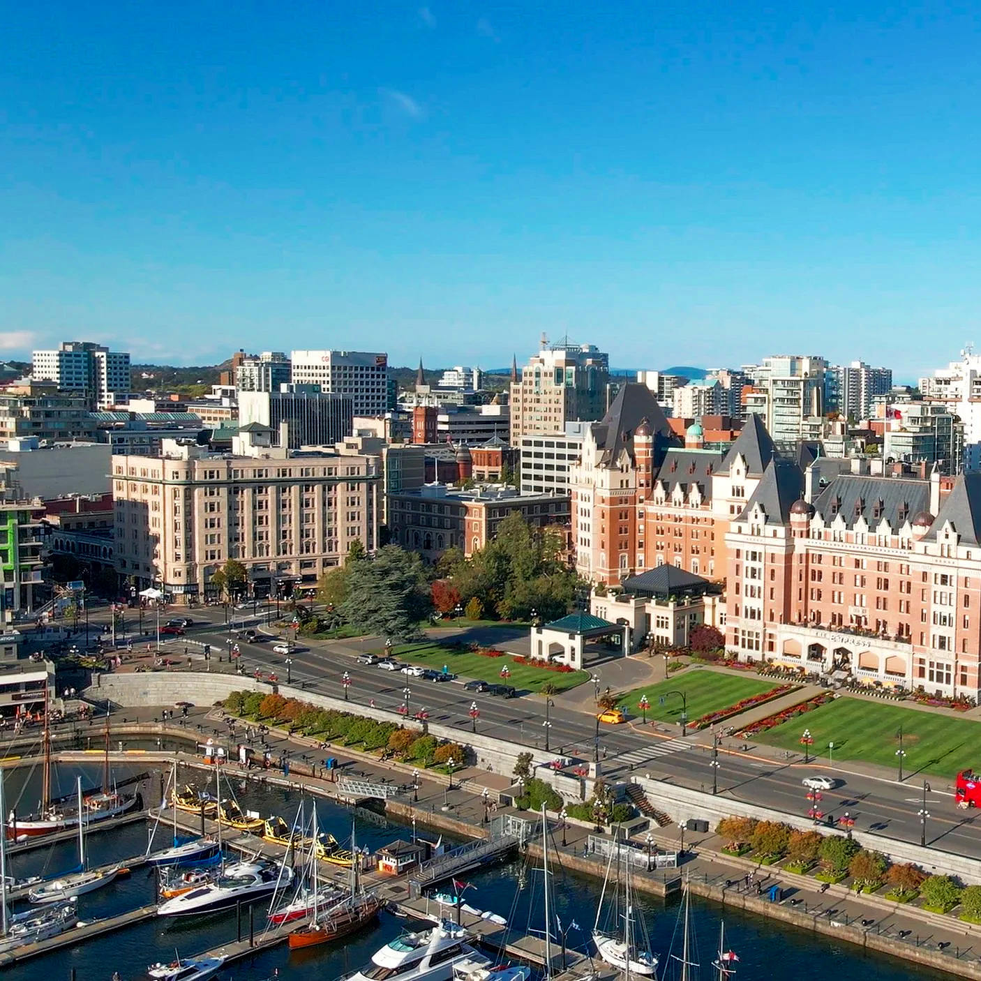 Cityscape with historic hotel, marina, and high-rise buildings under blue sky