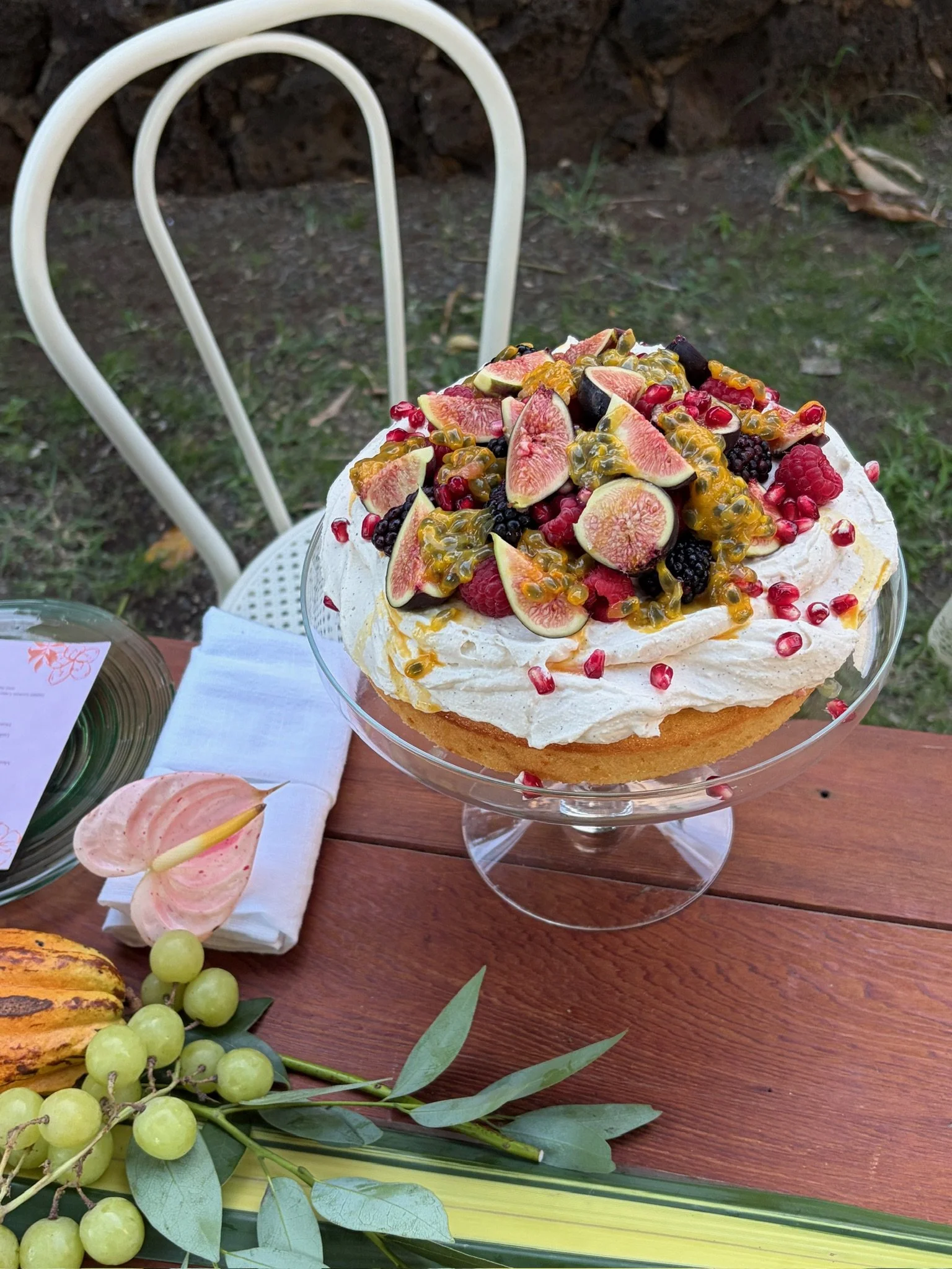 Italian lemon cake with whipped ricotta cream, figs, berries and pomegranate on a glass cake stand