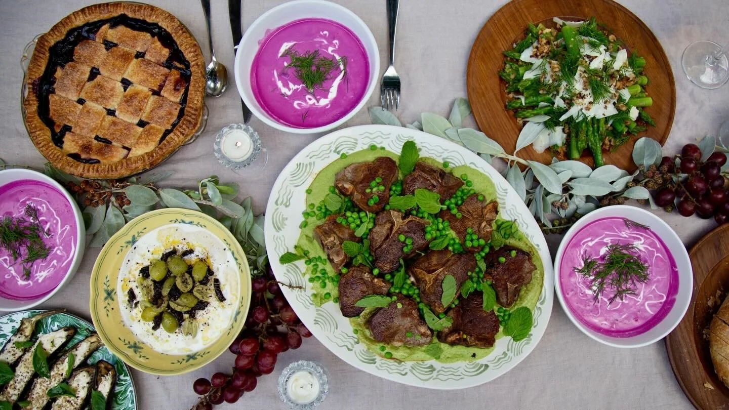 Overhead view of a private dinner spread with seared lamb and peas, chilled beet soup, olives with stracciatella and a lattice pie