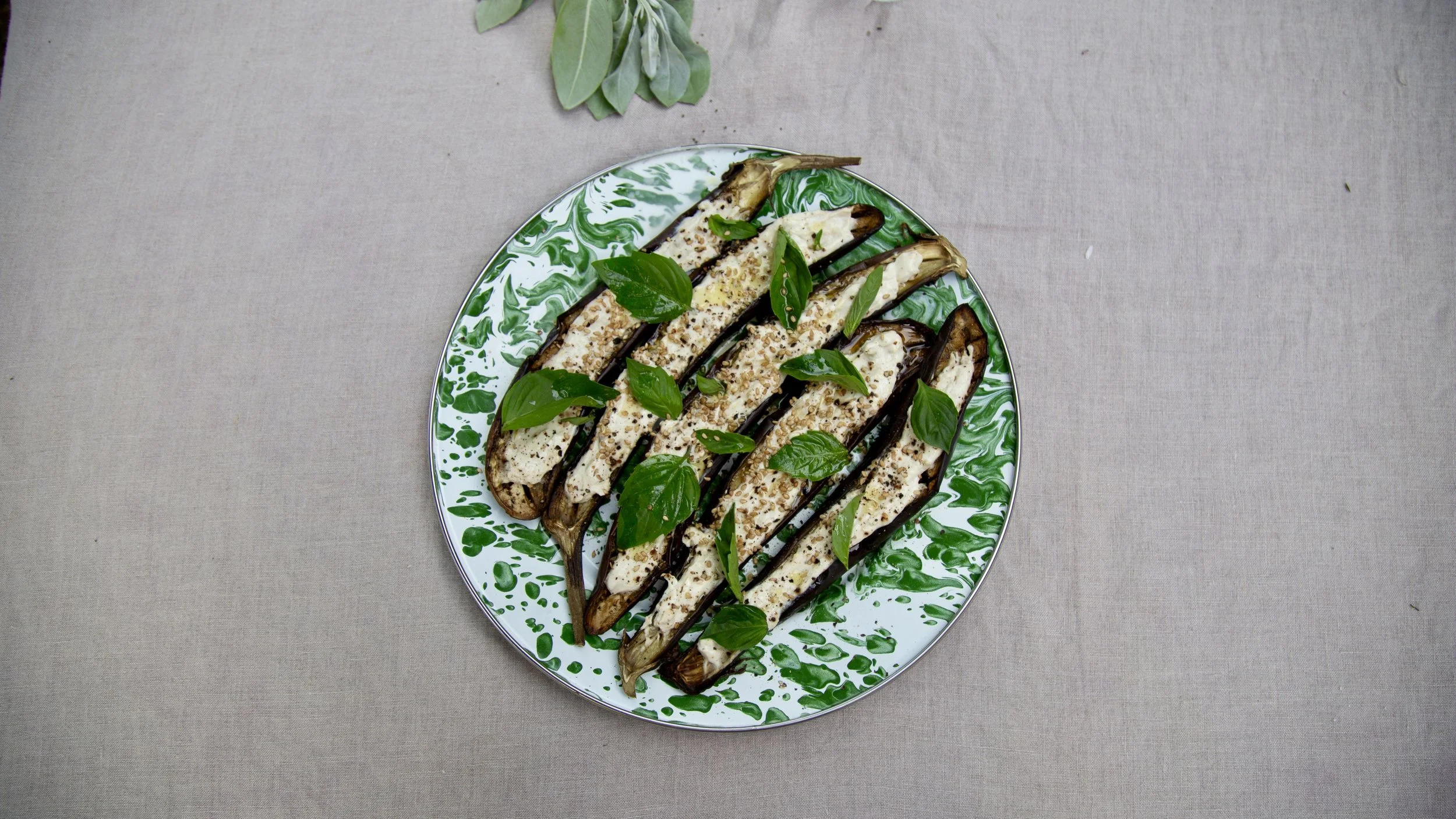 Grilled vegetables with fresh herbs on a green and white ceramic platter