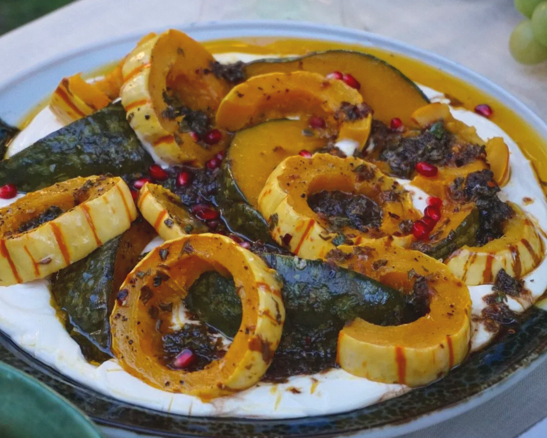Roasted delicata squash over yogurt with herb oil and pomegranate seeds