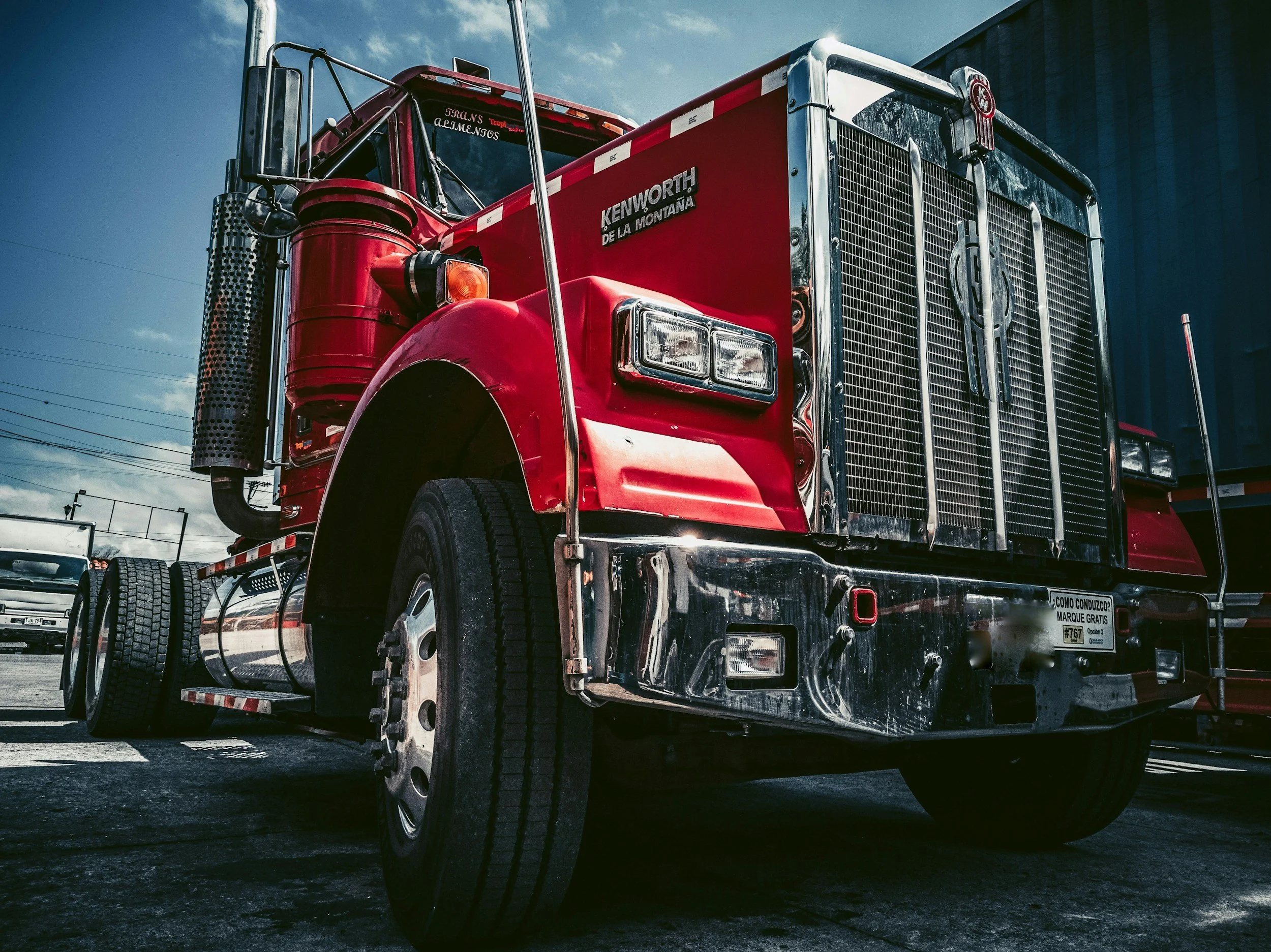 Red fire truck parked outdoors under a blue sky, with a large chrome grille and black tires.