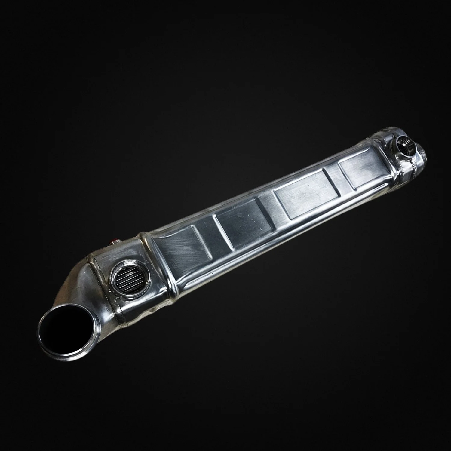 Metal exhaust muffler against a black background.