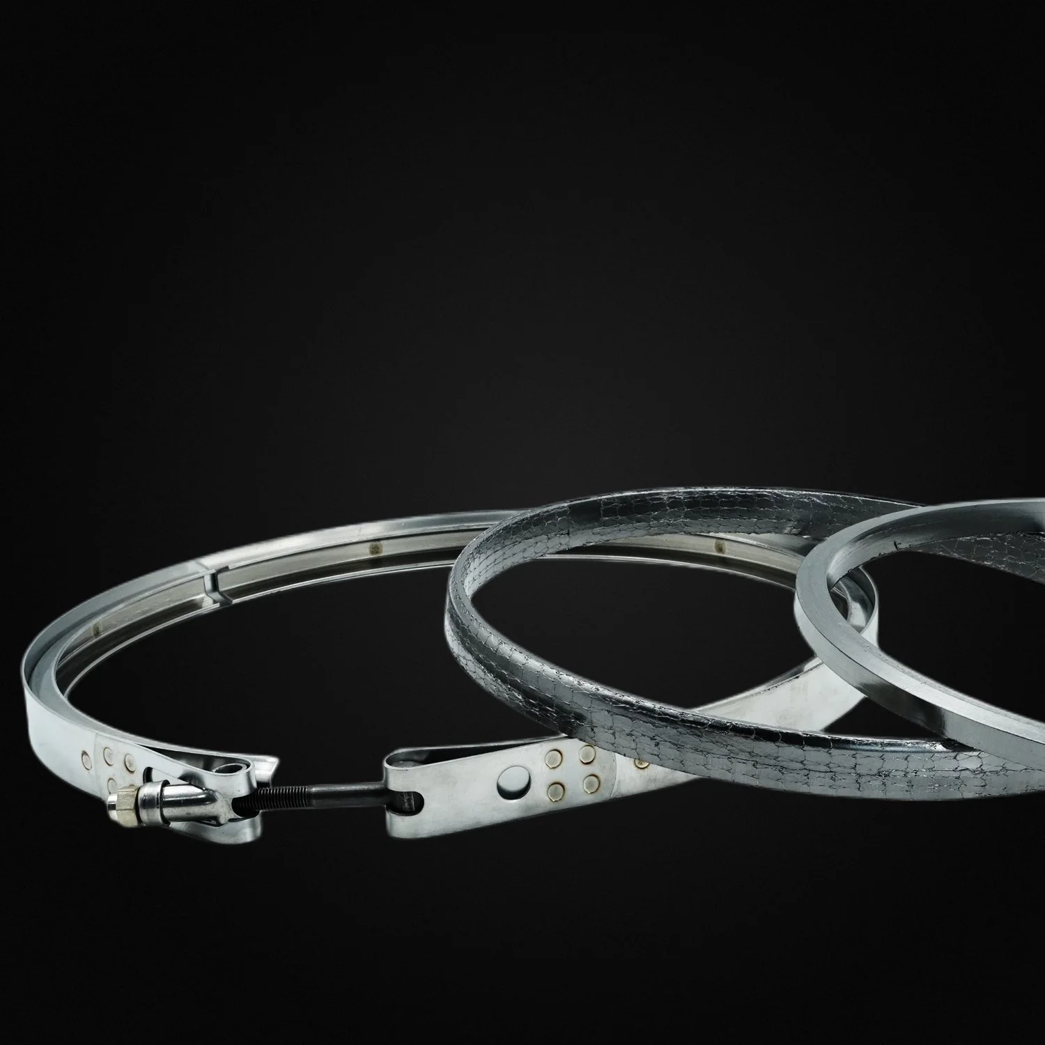 Three metallic headbands on a dark background, with varying textures and designs.