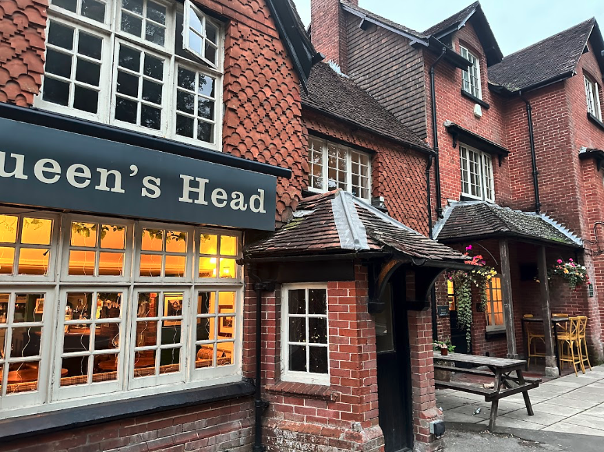 An old brick building with a sign for "Queen's Head".