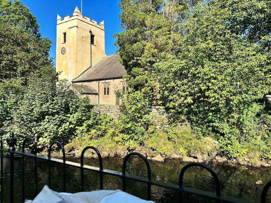 An old stone church sits among trees on a bubbling creek.
