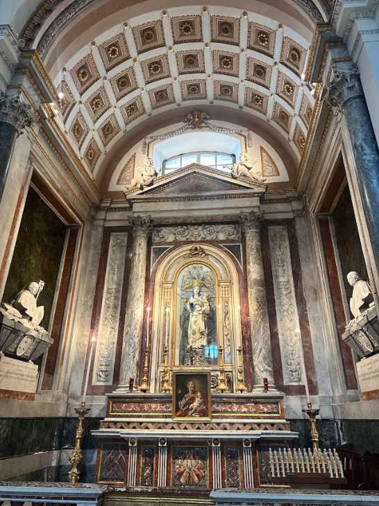 Interior of a historic chapel with an arched ceiling and artwork.